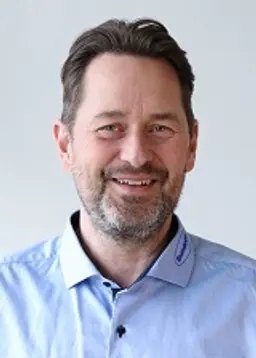 Portætfoto af Johnny Jensen salgschef hos Sunpack emballage. Han har sort hår og en blå skjorte på