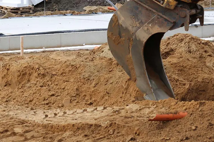 Gravemaskine fjerner jord på byggeplads for at forberede kloakering til terrændæk