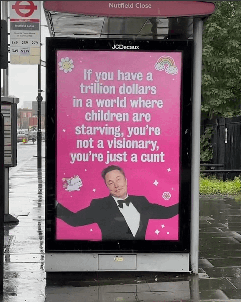 London bus stop poster depicting a shrugging Elon Musk wearing evening attire with "If you have a trillion dollars in a world where children are starving, you're not a visionary, you're just a cunt" in white block letters.
