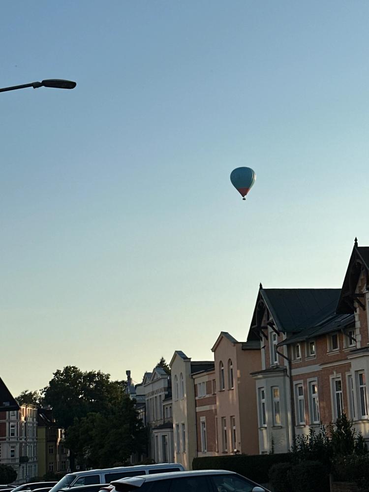 A hot air balloon in the sky illuminated by the setting sun