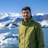Karan Hudia mid-request to hold the camera differently with the Arctic ice in the background