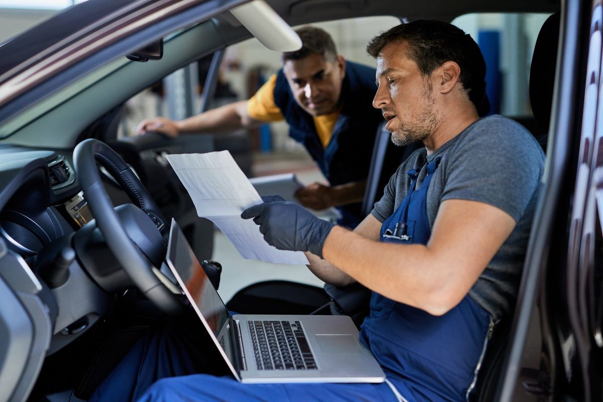 Mechanic reviewing vehicle inspection paperwork for an insurance claim