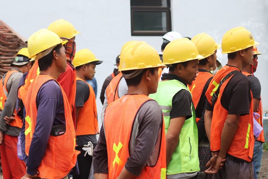 Construction worker wearing orange Class 3 hi-vis jacket with reflective strips on building site