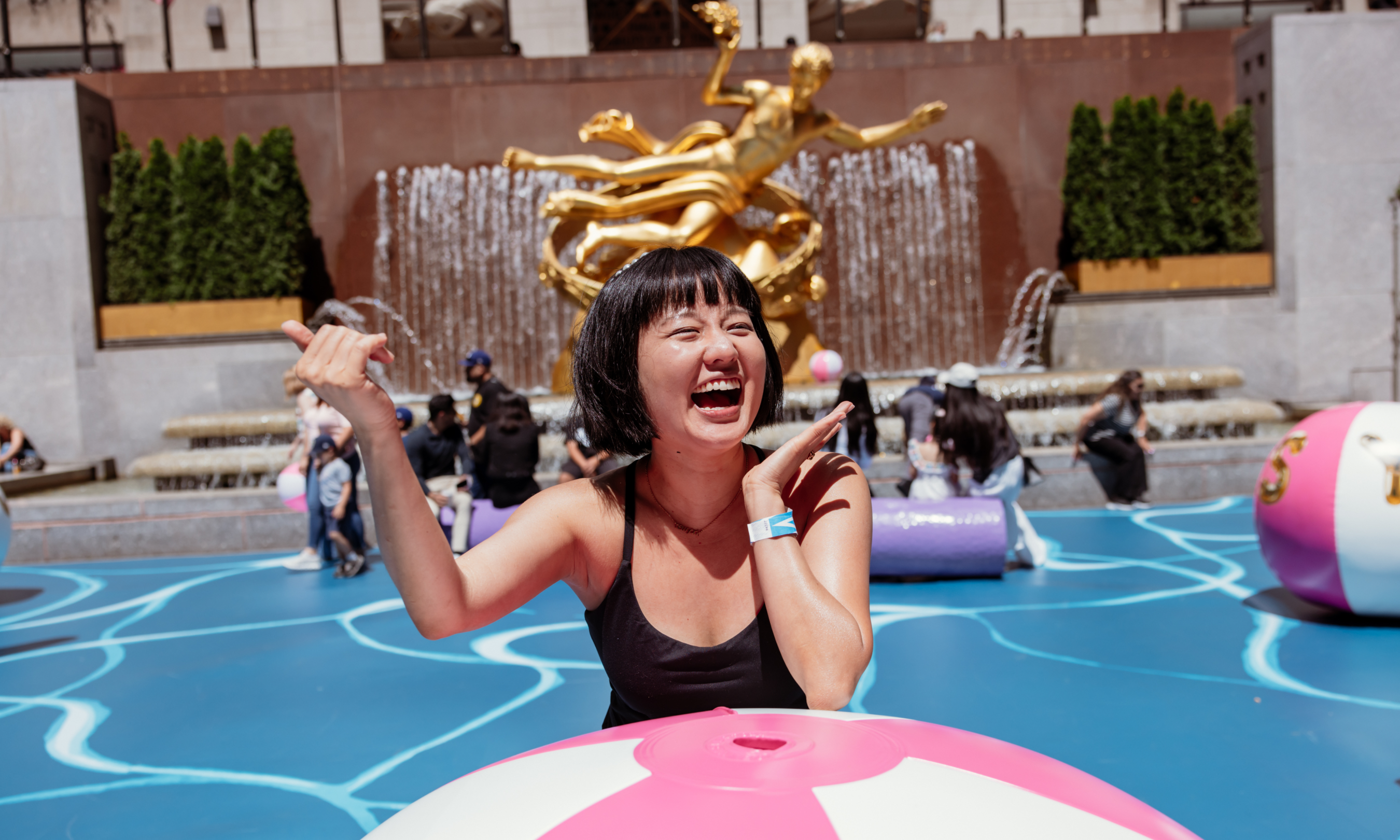 Woman laughing and posing behind a giant beach ball at Joel Mesler's "Pool Party"