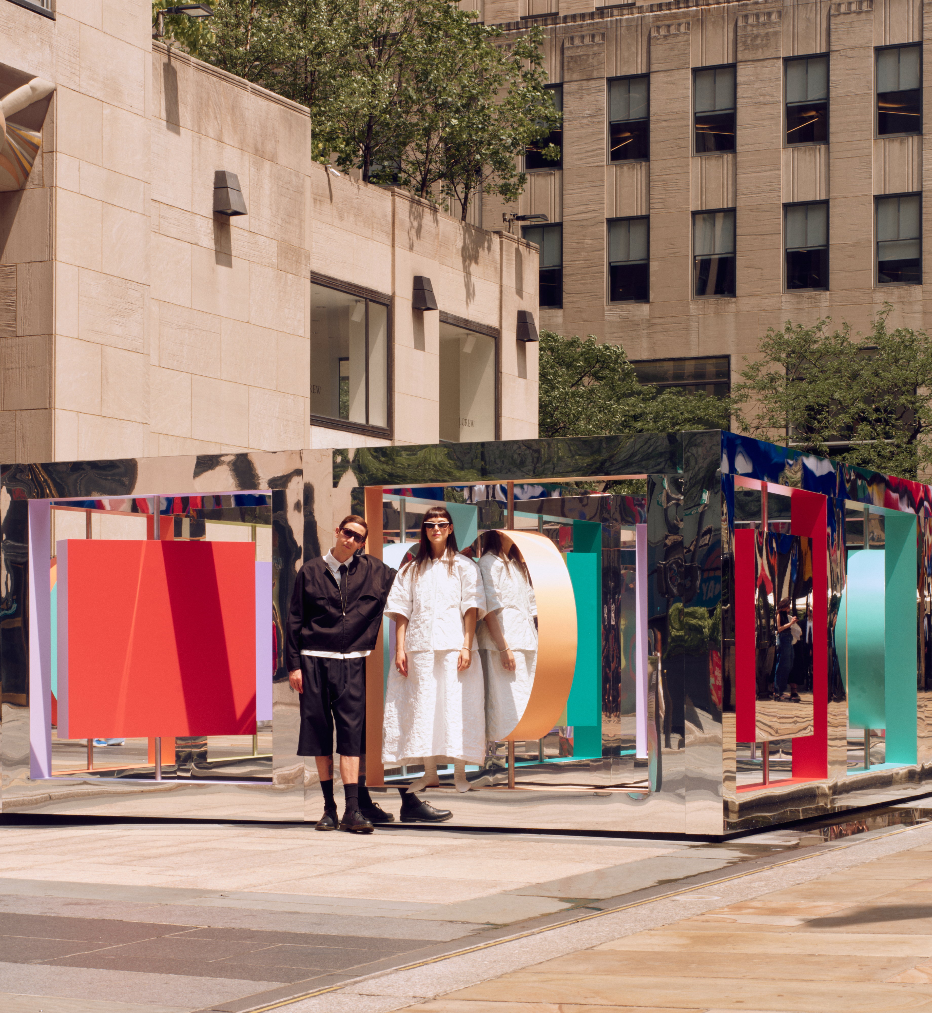 Artist duo Wade and Leta standing next to "Reflection Point," their newest sculpture on display on Center Plaza