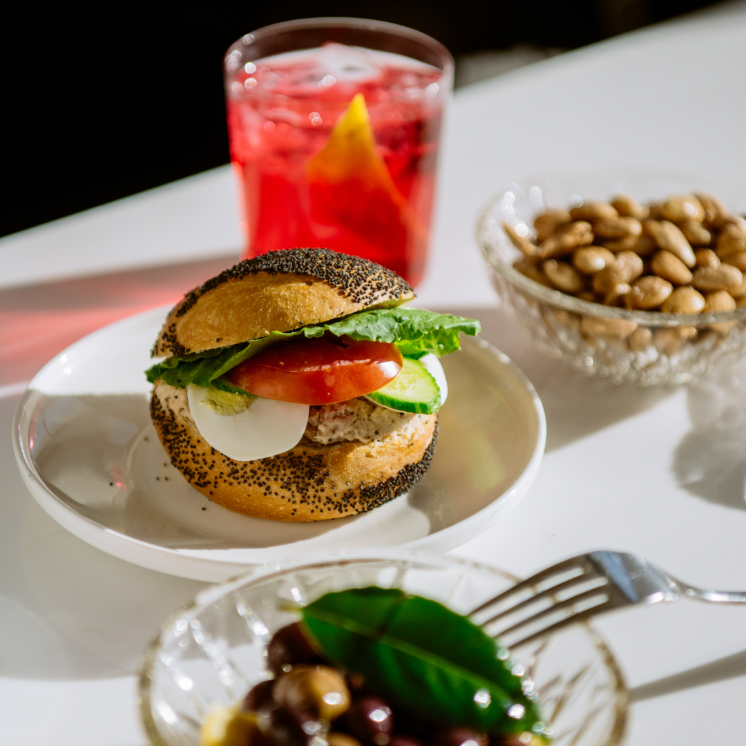 A cocktail and plates of food available at The Weather Room at Top of the Rock