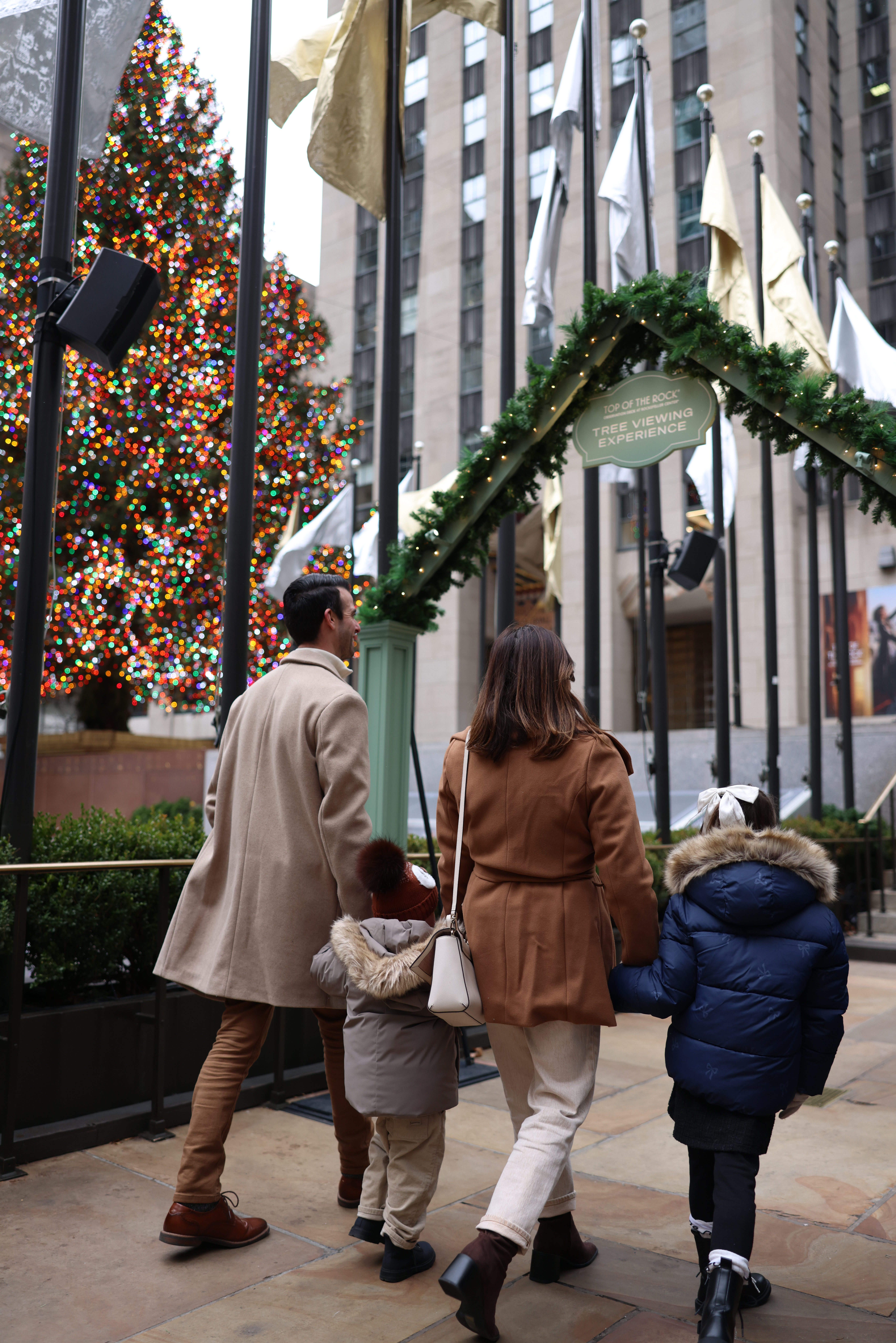 a Family walking towards the Rock Center Christmas Tree