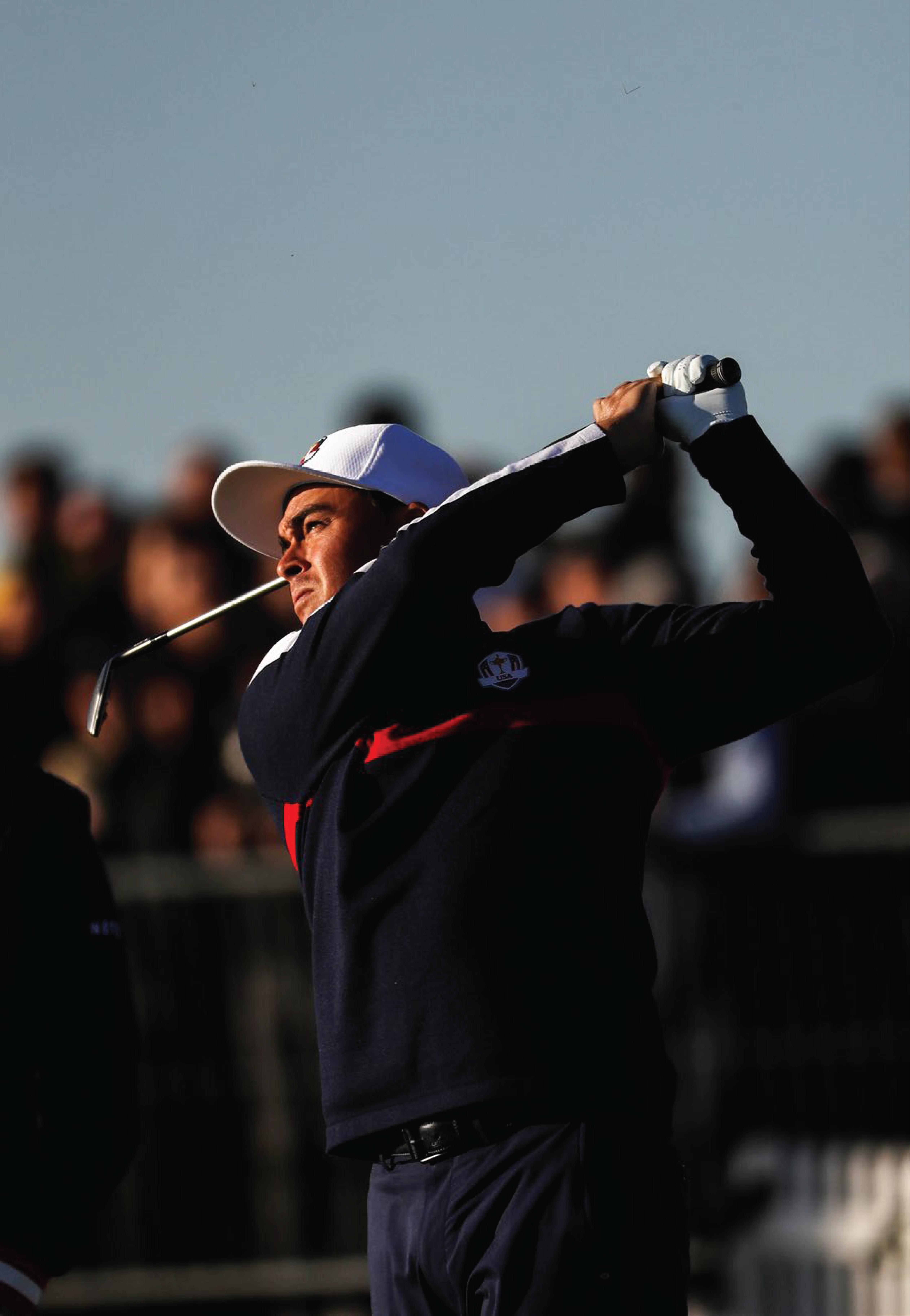 man in a white hat hitting a golf ball
