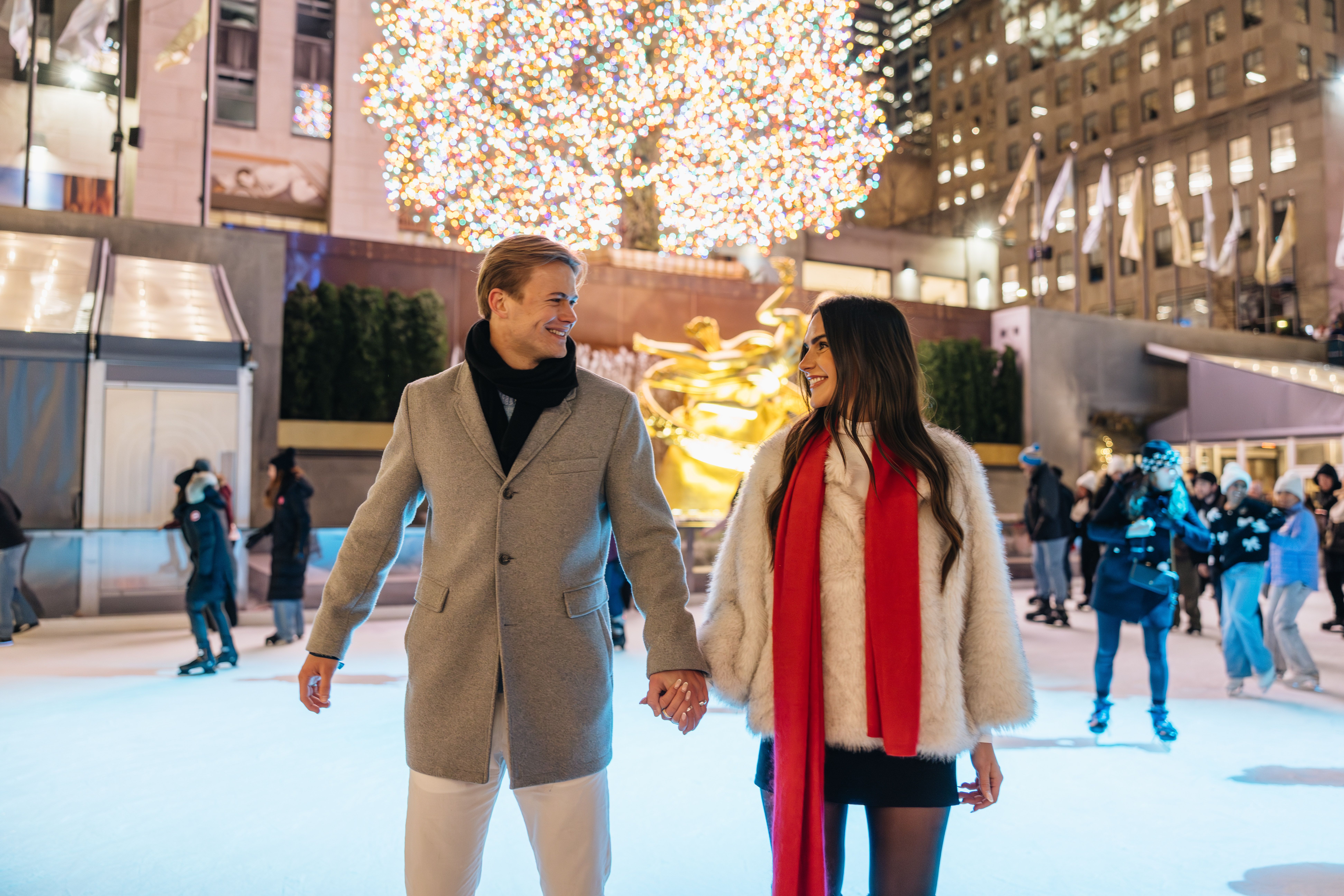 a man and woman holding hands skating together on the rink