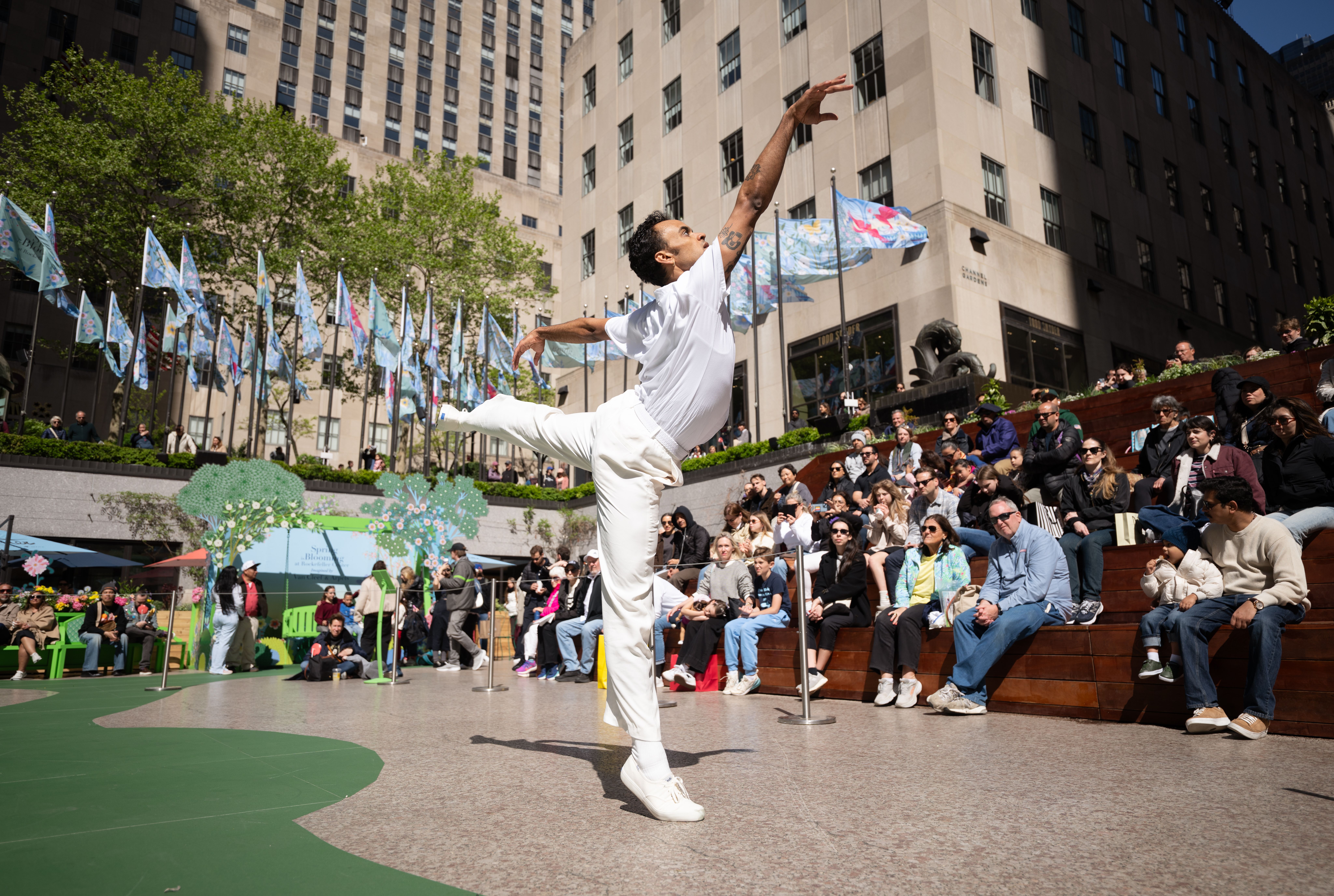 A dancer in all white doing contemporary dance during the Van Cleef & Arpels Spring is Blooming installation at Rockefeller Center