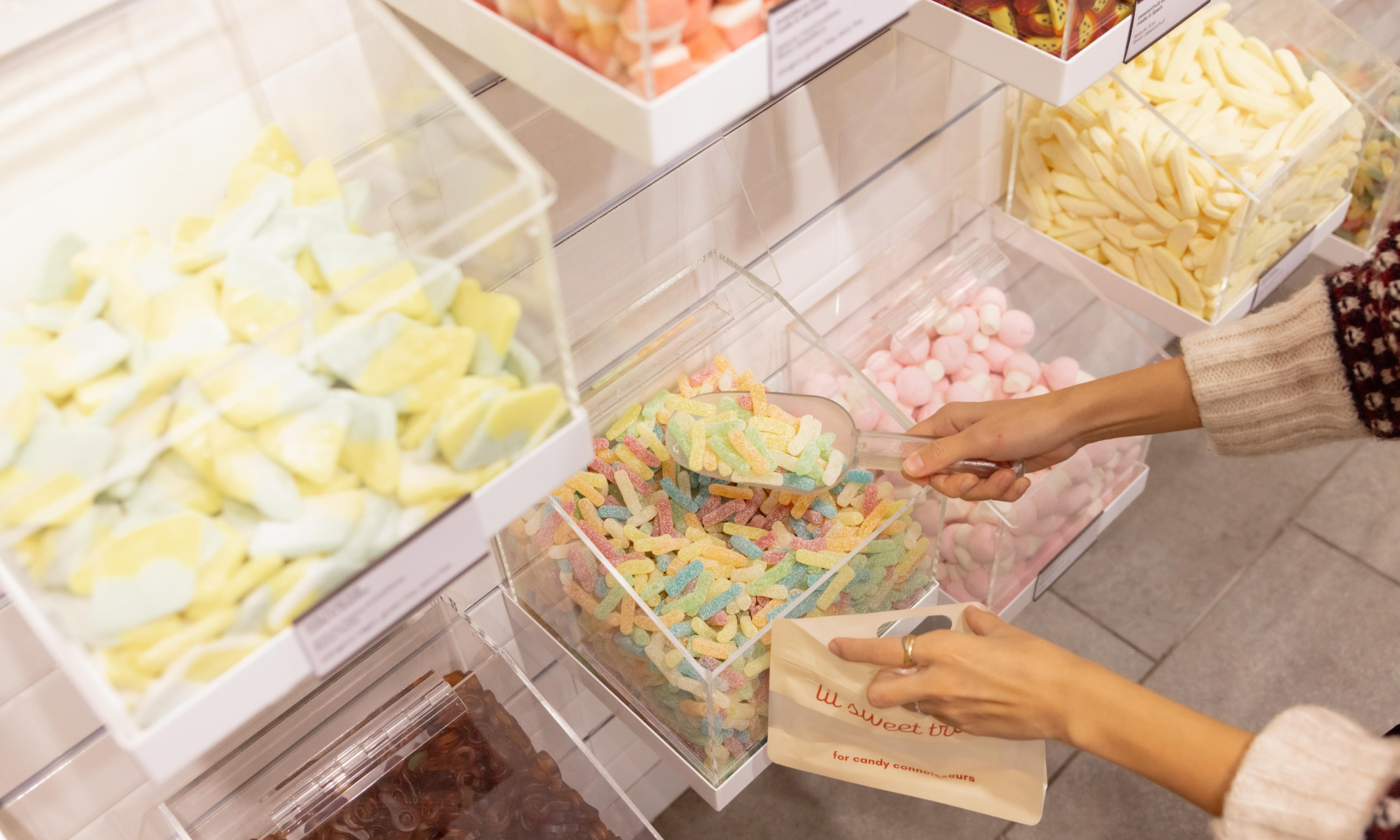 Hands scooping candy into a bag at lil sweet treat at Rockefeller Center