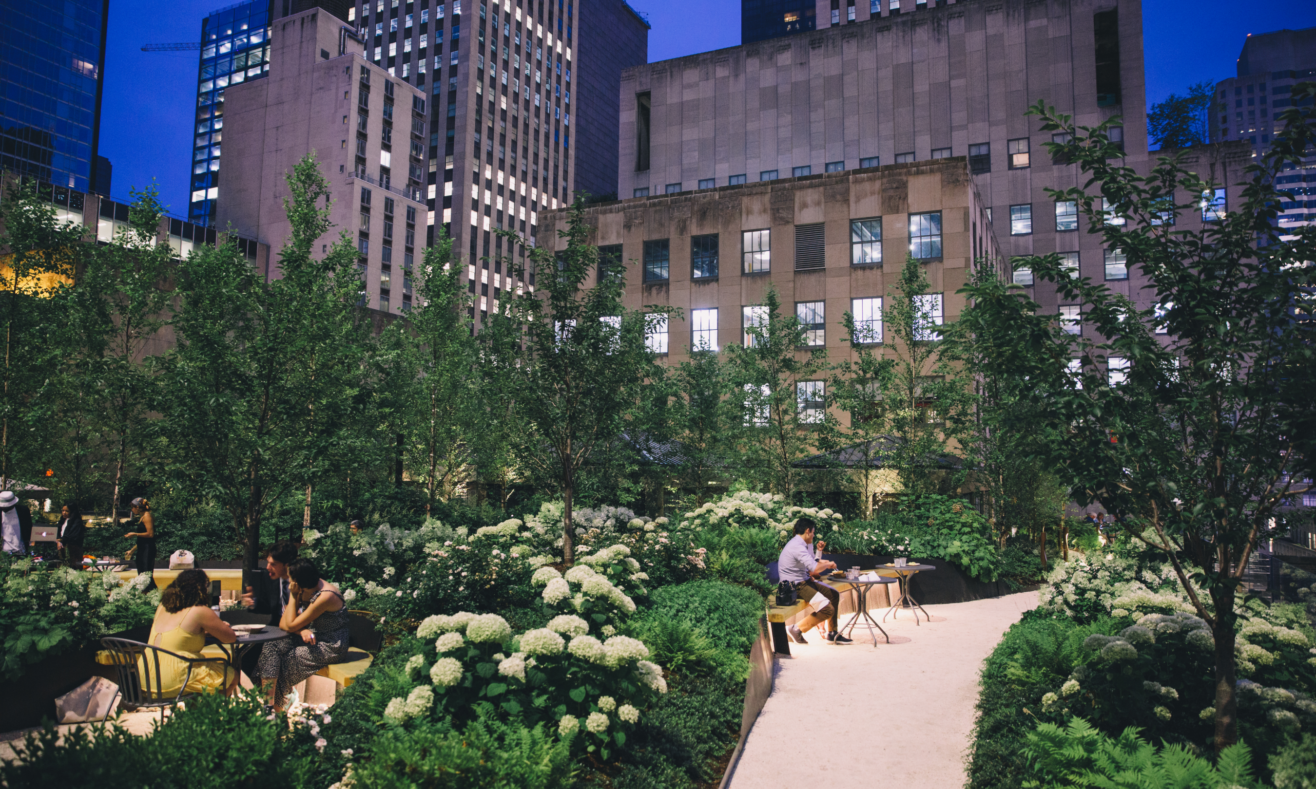 People sitting at tables at Radio Park at dusk