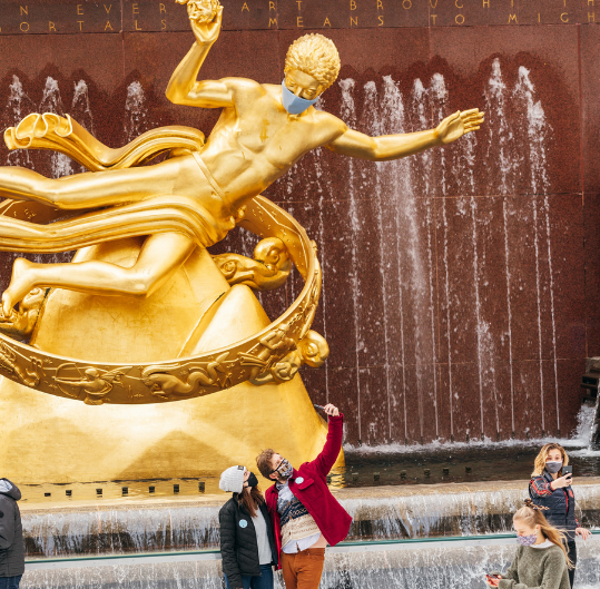 A couple taking a picture in front of Prometheus under at the Rockefeller Center Ice Rink
