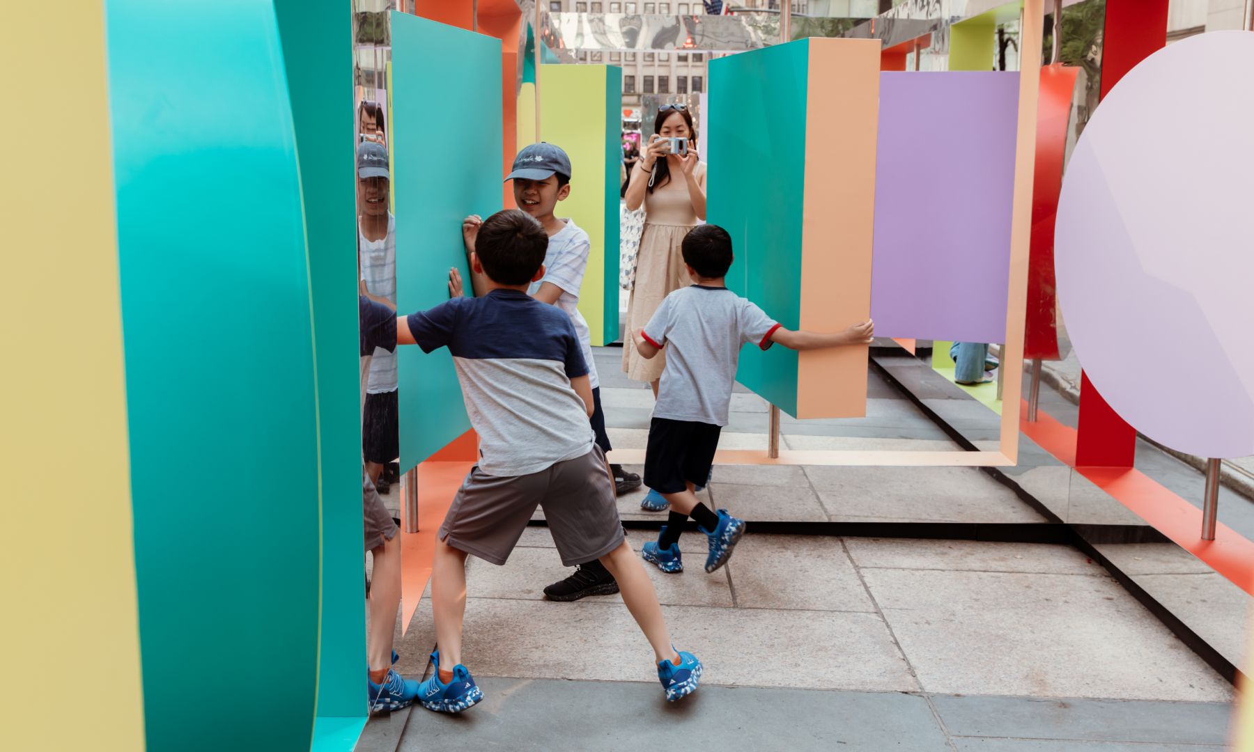 Three children playing inside Wade and Leta's interactive public art piece "Reflection Point"