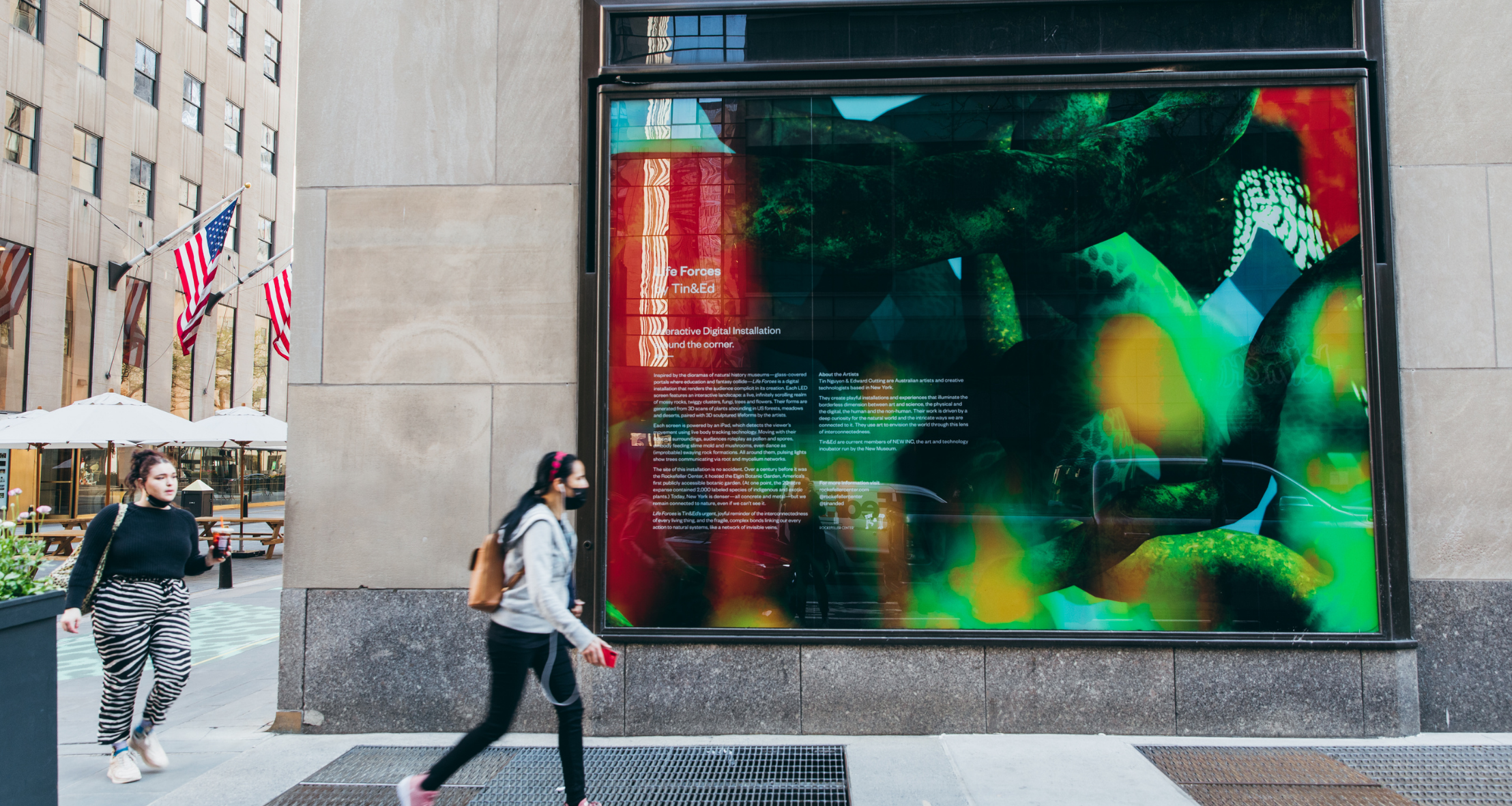 Two young girls walking by the Life Forces museum at Rockefeller Center. 