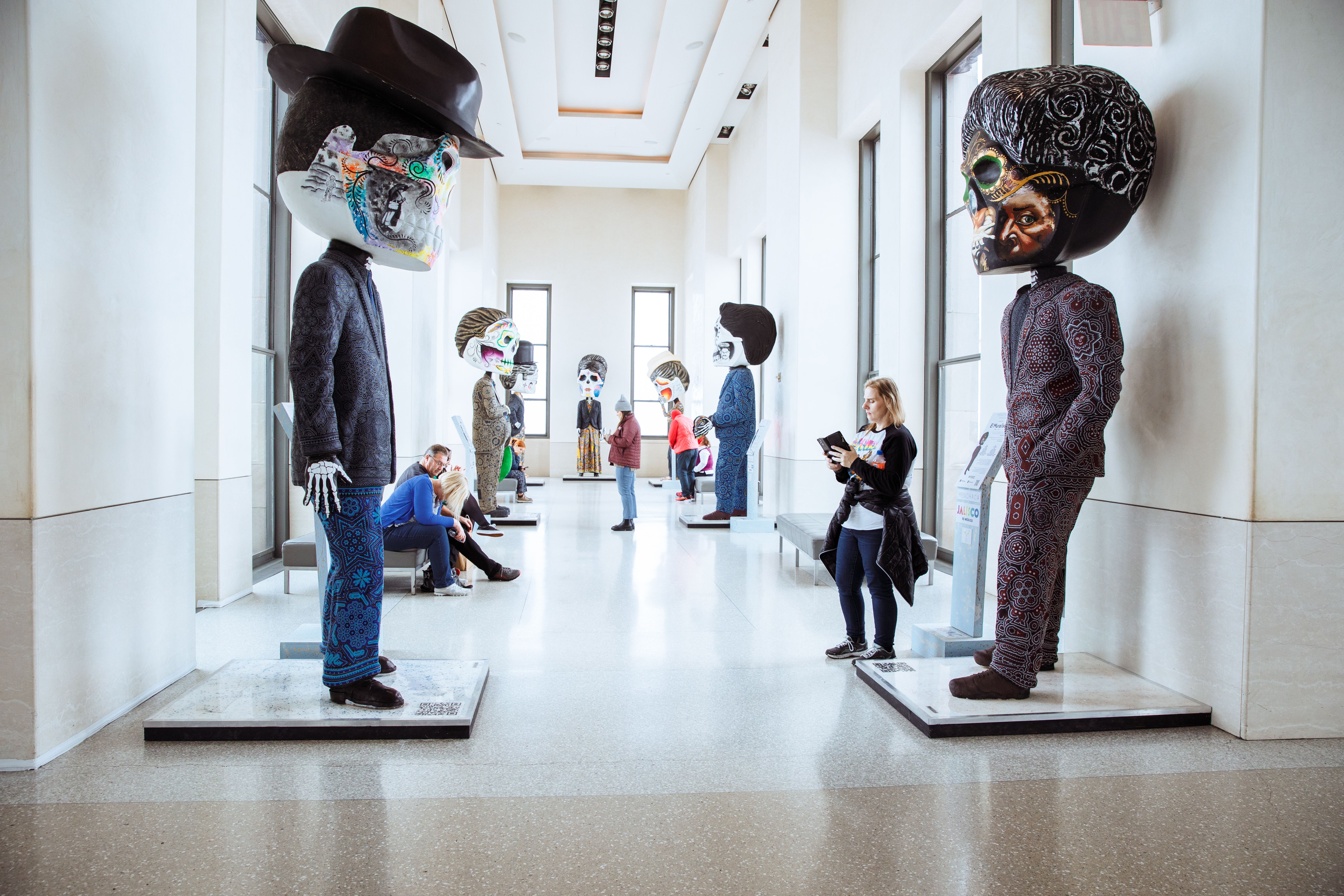 People standing by the catrina sculptures on display at Top of The Rock in honor of Mexico Week