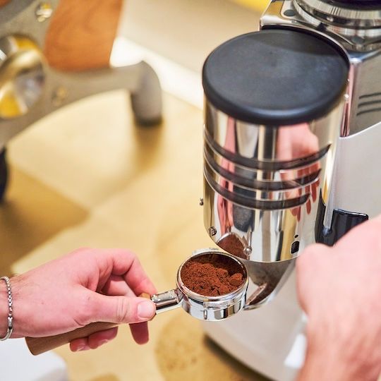 % Arabica employee putting coffee grounds in a portafilter