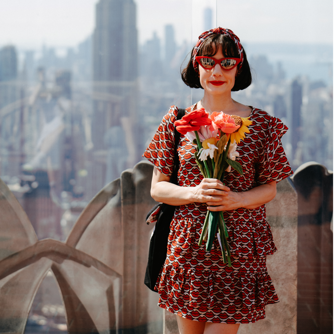 A woman holding a bouquet of fake flowers at Top of the Rock