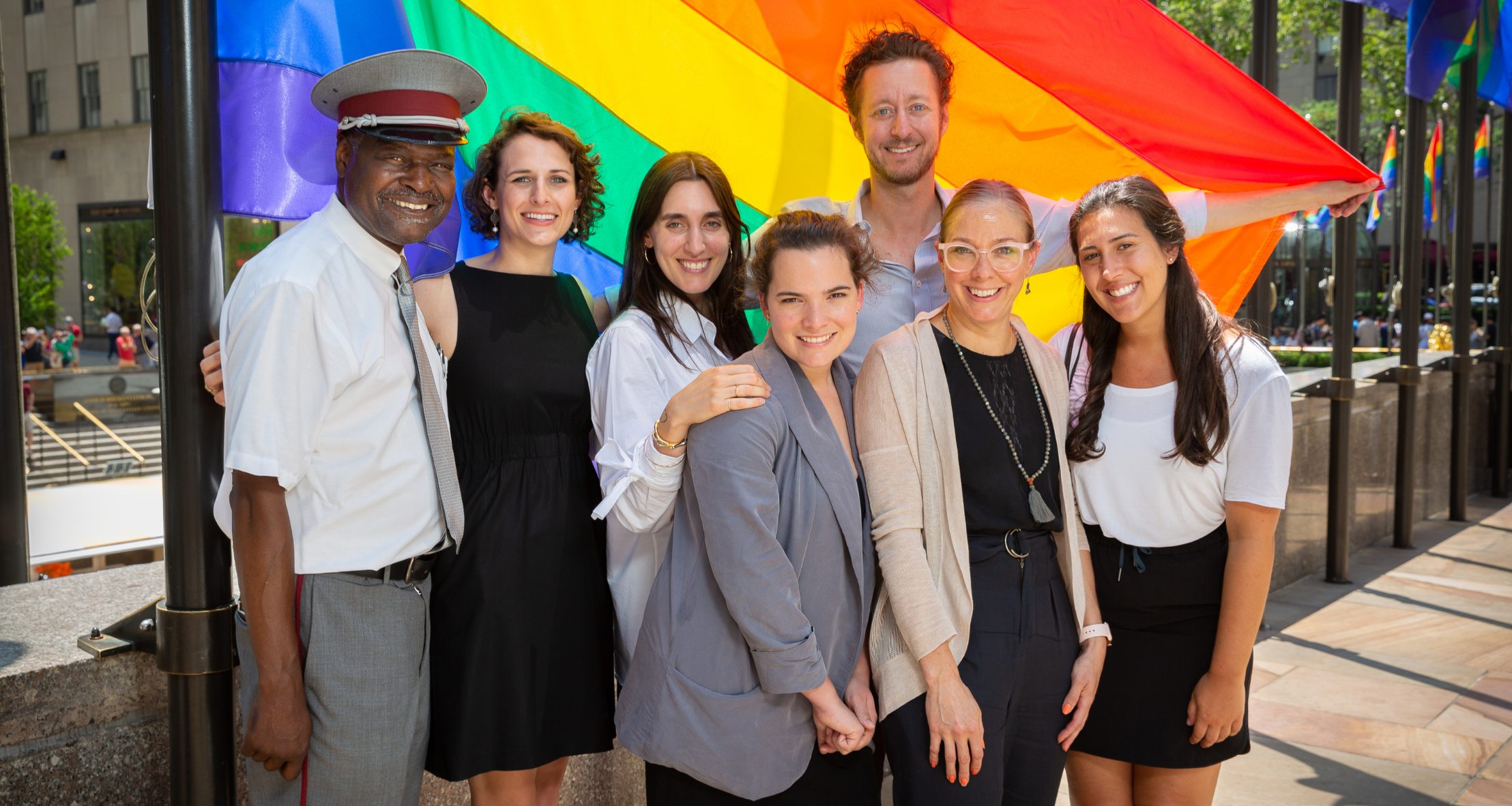 CJ welcoming visitors to the plaza during pride month with rainbow flags arounds the rink.