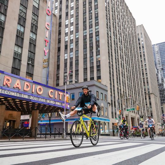 Person riding a bike in front of Radio City Music Hall during the TD Five Boro Bike Tour