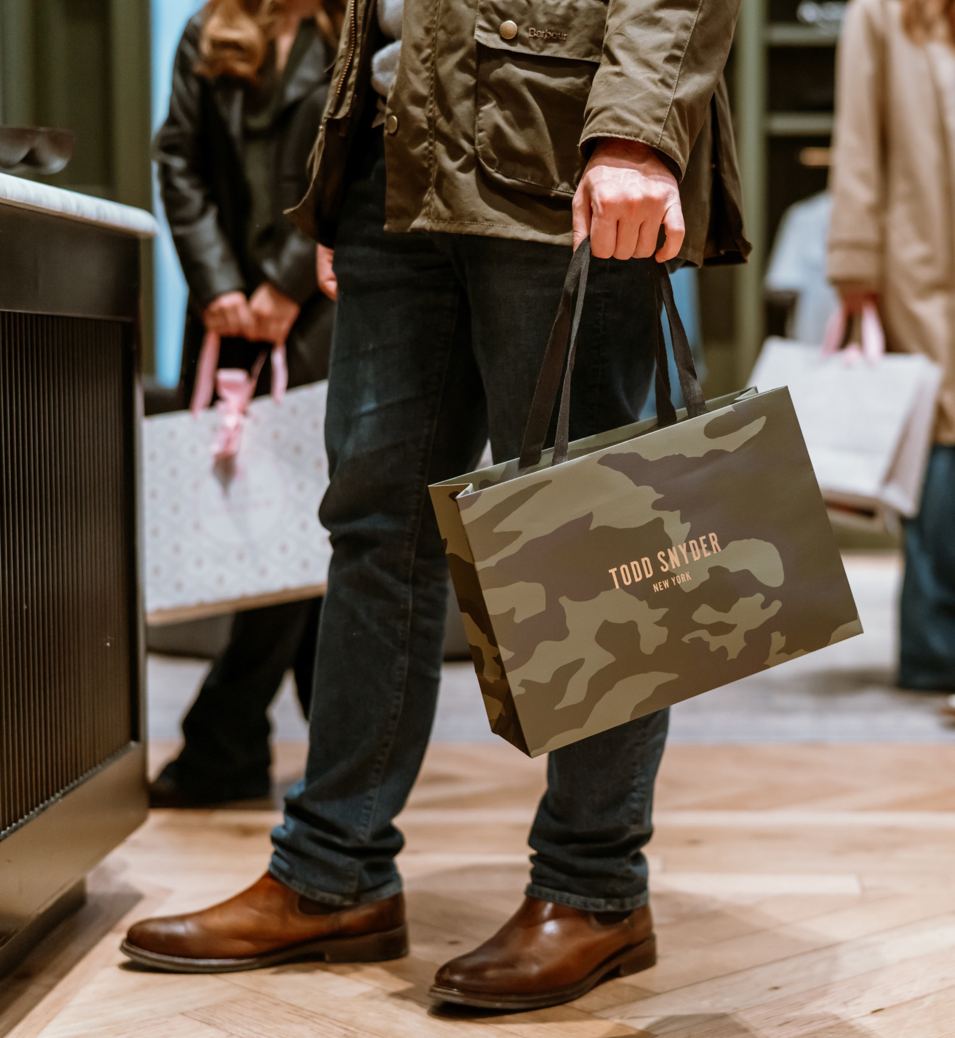 A close-up of a hand holding a Todd Snyder shopping bag