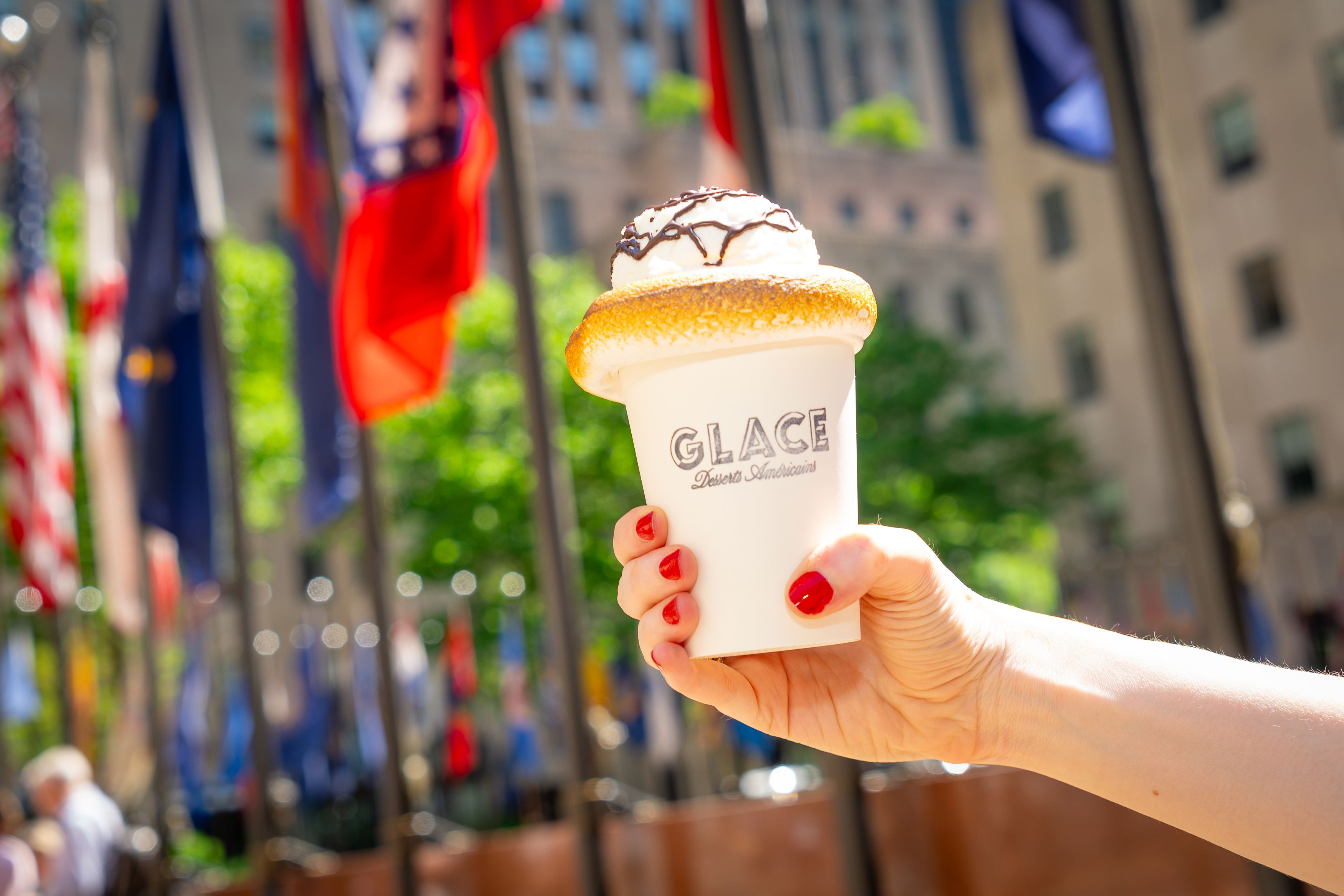 Glace iced hot chocolate being held up in front of the flags at Rockefeller Center