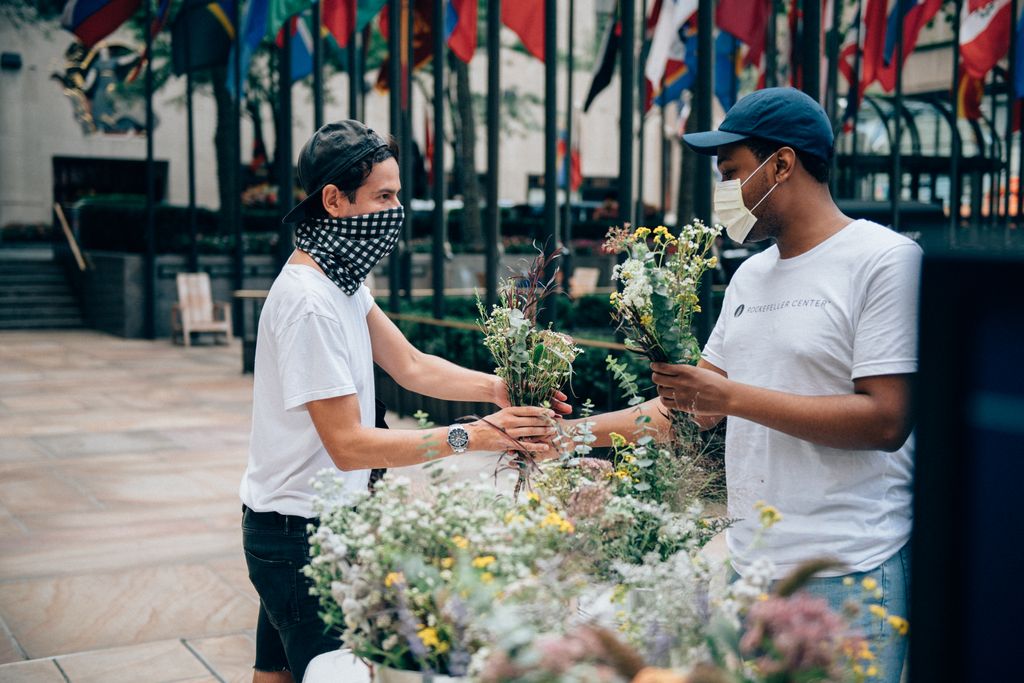 At a Rockefeller Center pop-up event, a man hands another man flowers