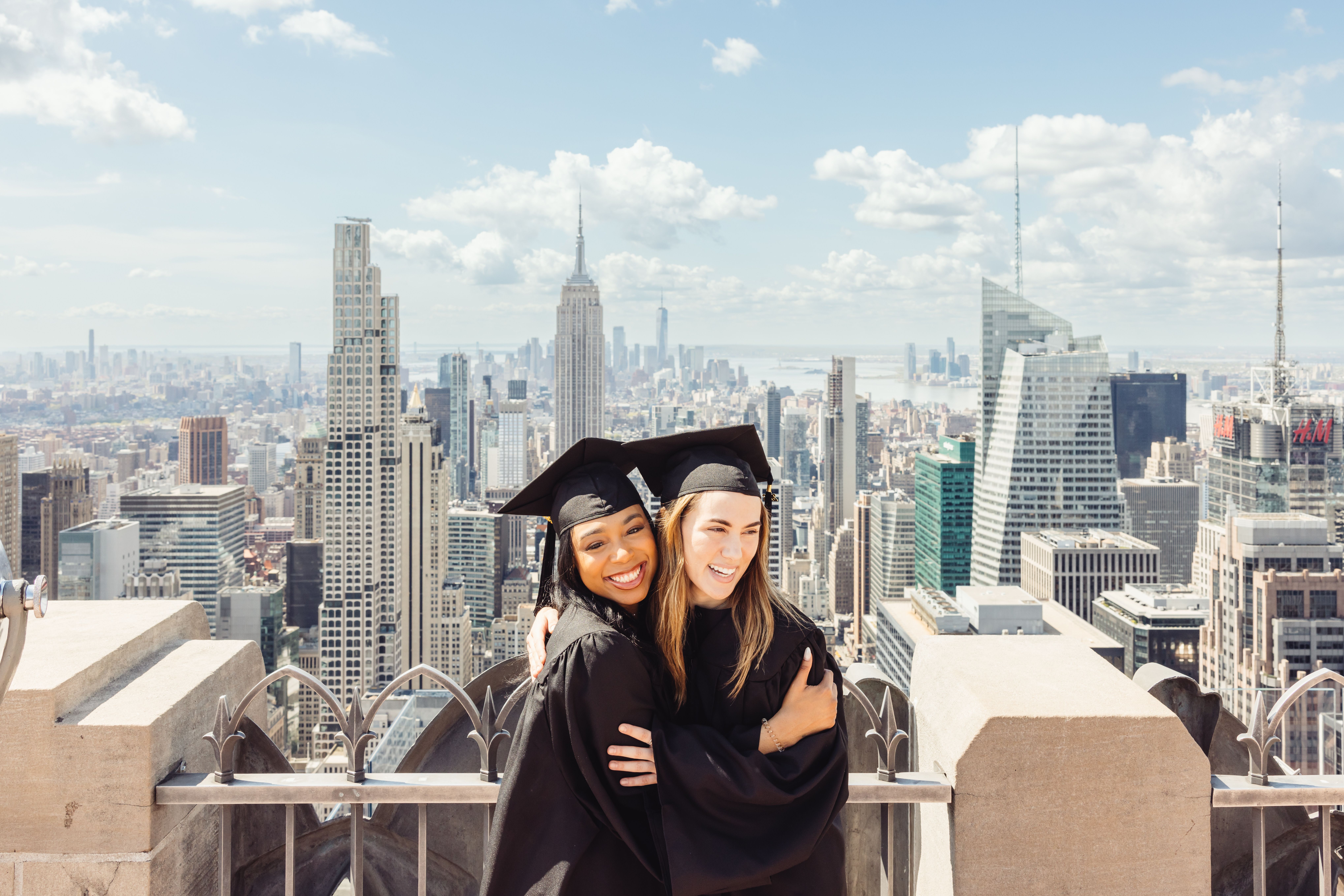Two graduates at Top of the Rock in their cap and gown