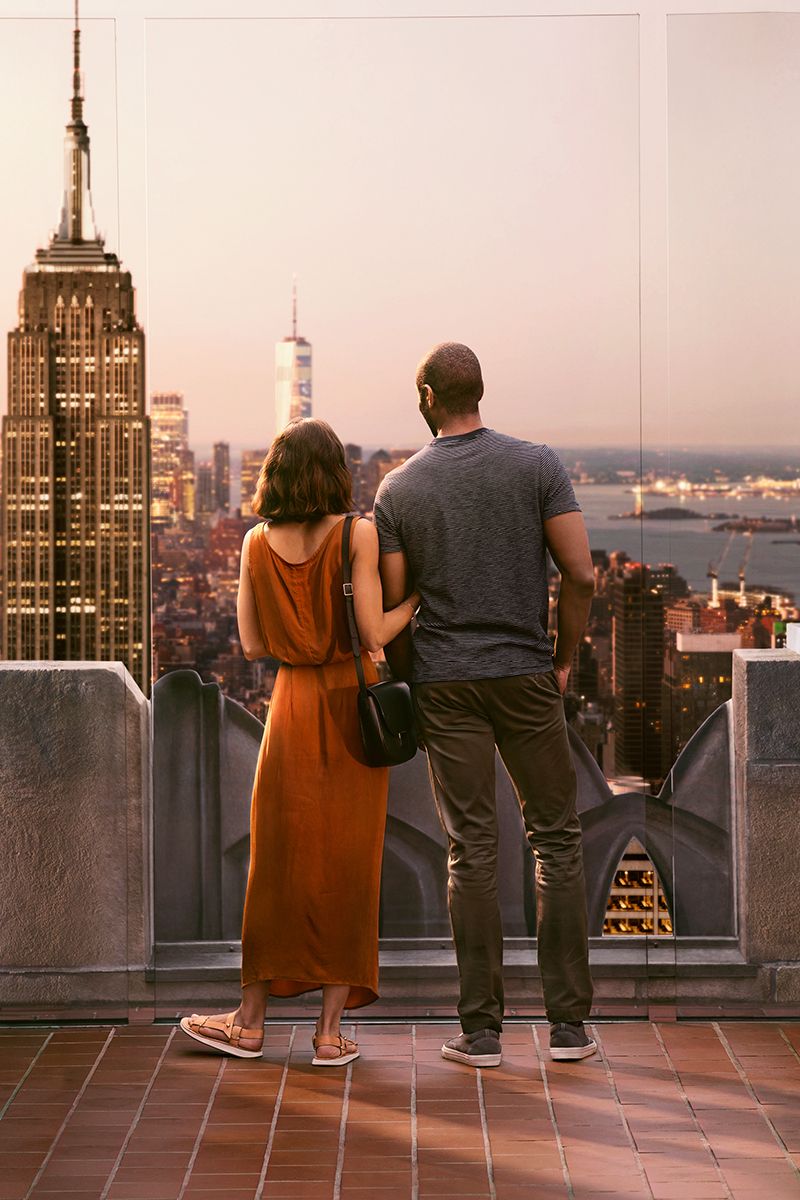 Una pareja se abraza mientras observa una romántica puesta de sol desde Top of the Rock.