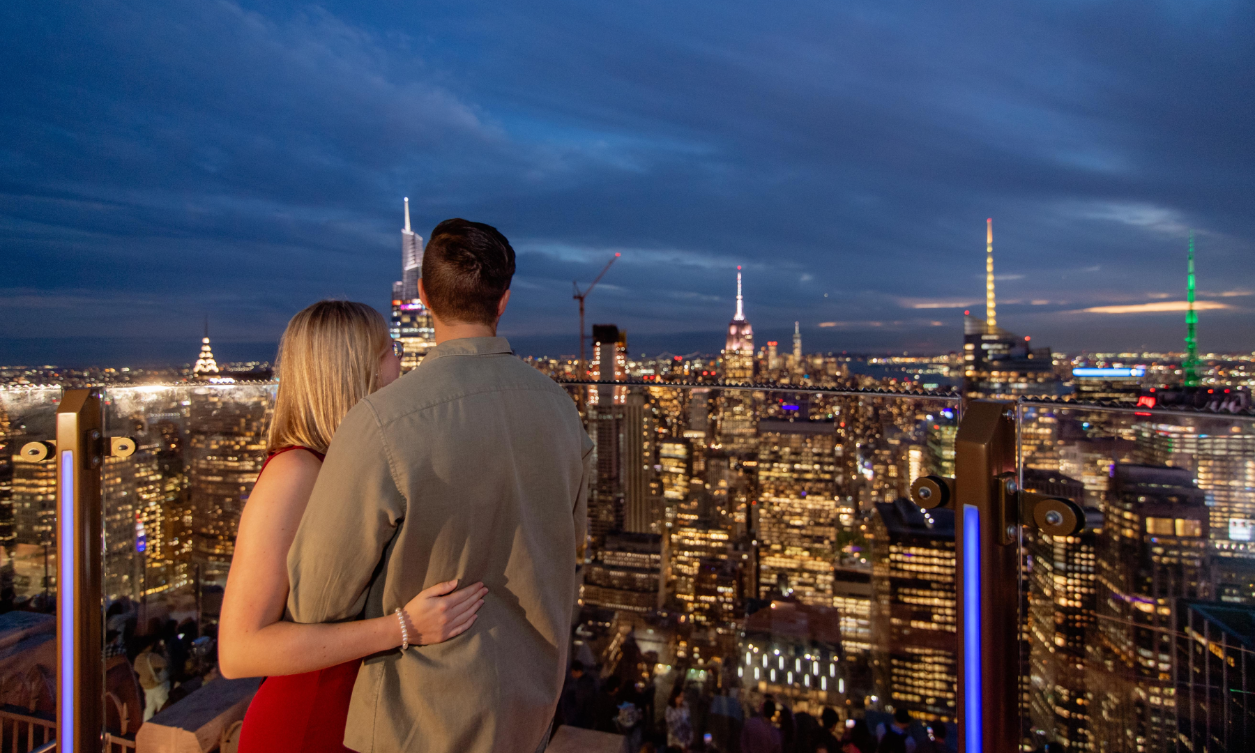 A couple looking at the New York City skyline at night on Skylift