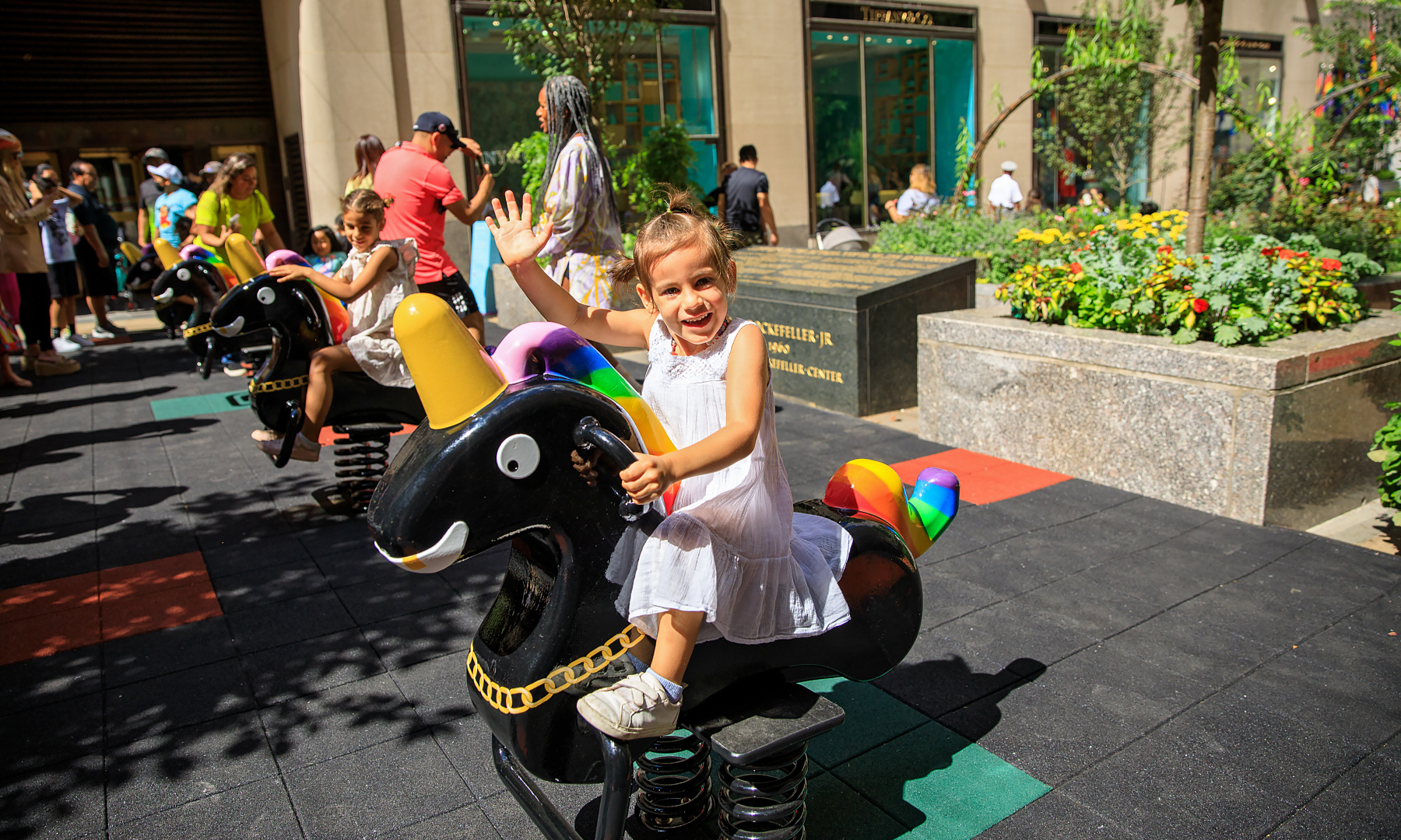 A small child sits on Derrick Adam's "Funtime Unicorns" interactive sculpture