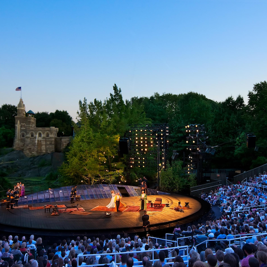 Crowd watching a performance of Shakespeare in the Park at the Delacorte Theater in Central Park