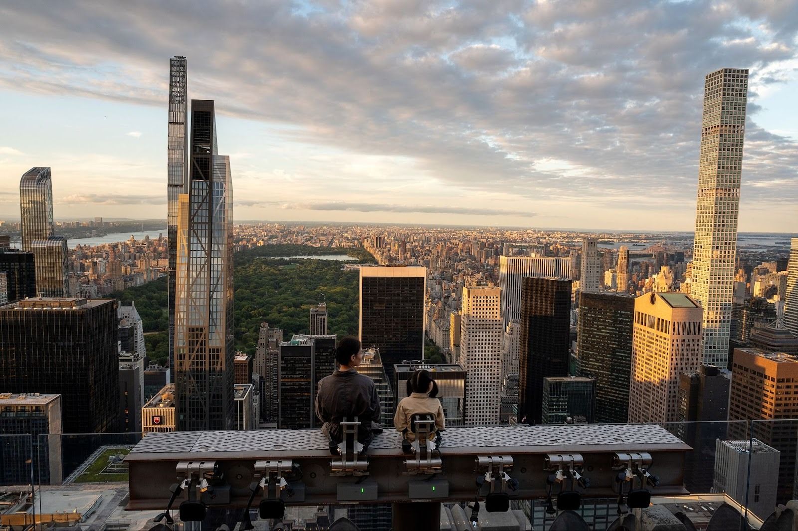 two people sitting on the beam overlooking the city