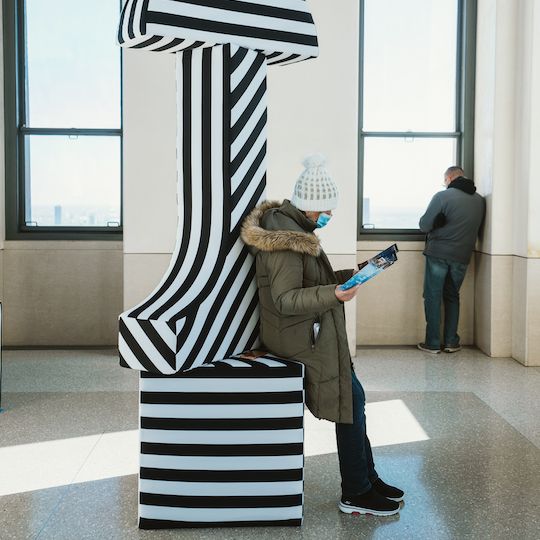 Person sitting on a pillar in Kris Moran and Martin Duffy's art installation at Top of the Rock