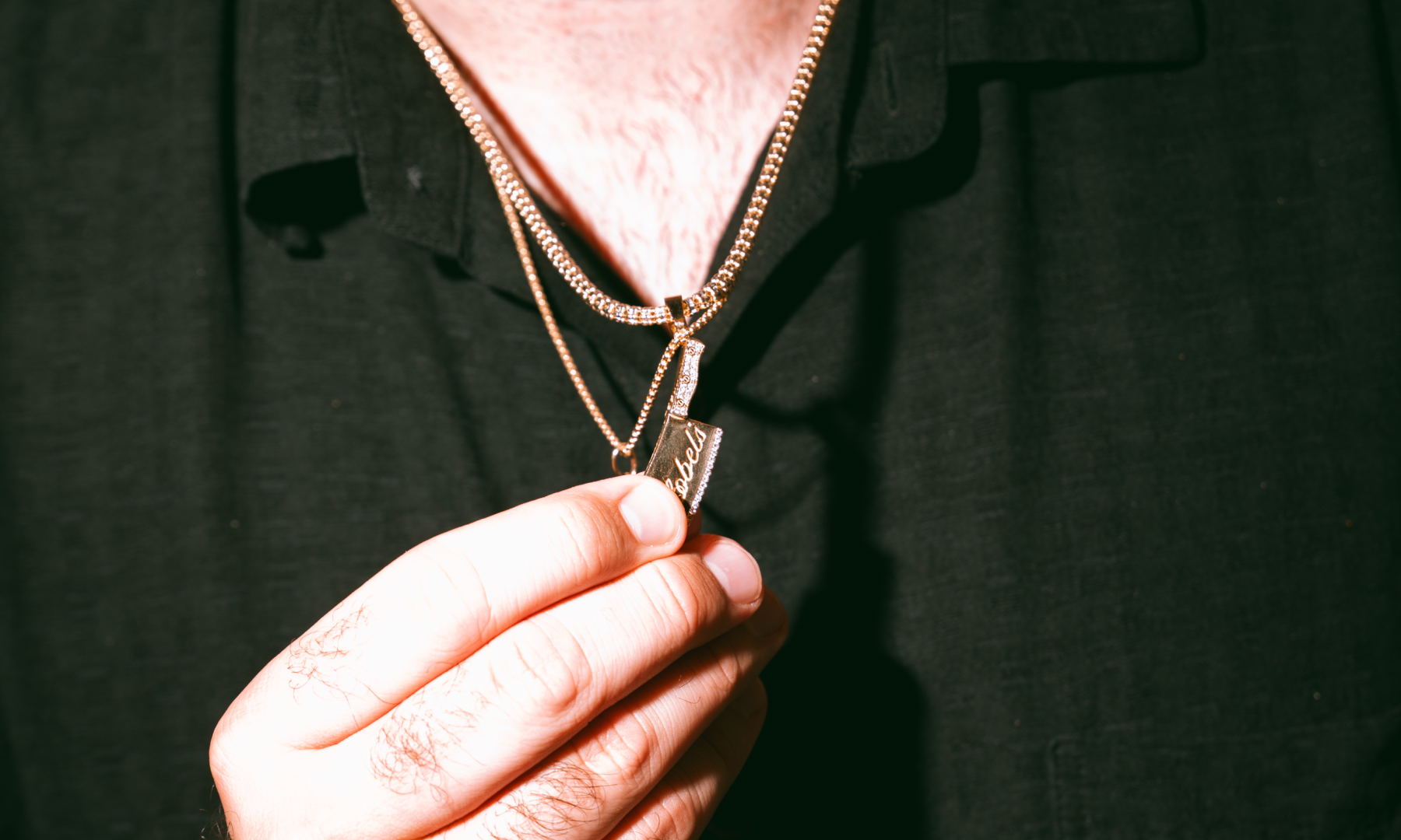 A close-up of Brian Lobel's necklace with butcher's knife charm engraved with his last name