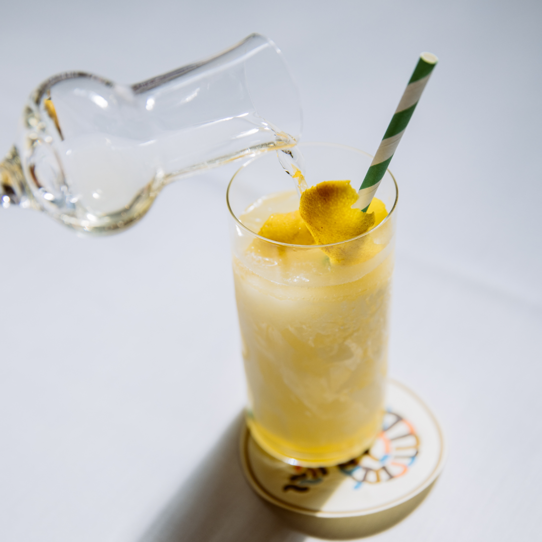 Hand pouring champagne into a cocktail from Jupiter at Rockefeller Center