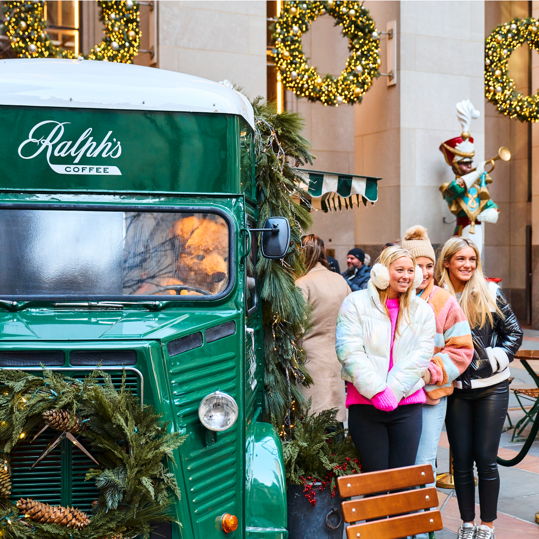 Three women taking a photo in front of the Ralph's Coffee Truck at Rockefeller Center