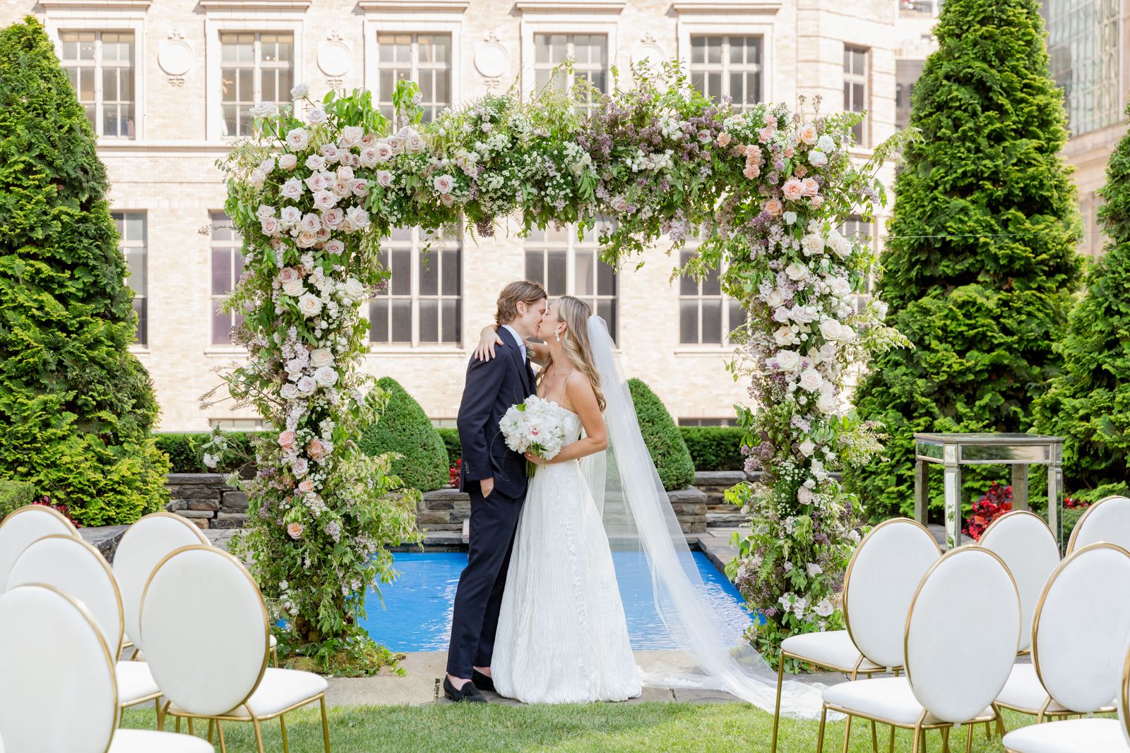 couple kissing under wedding arch