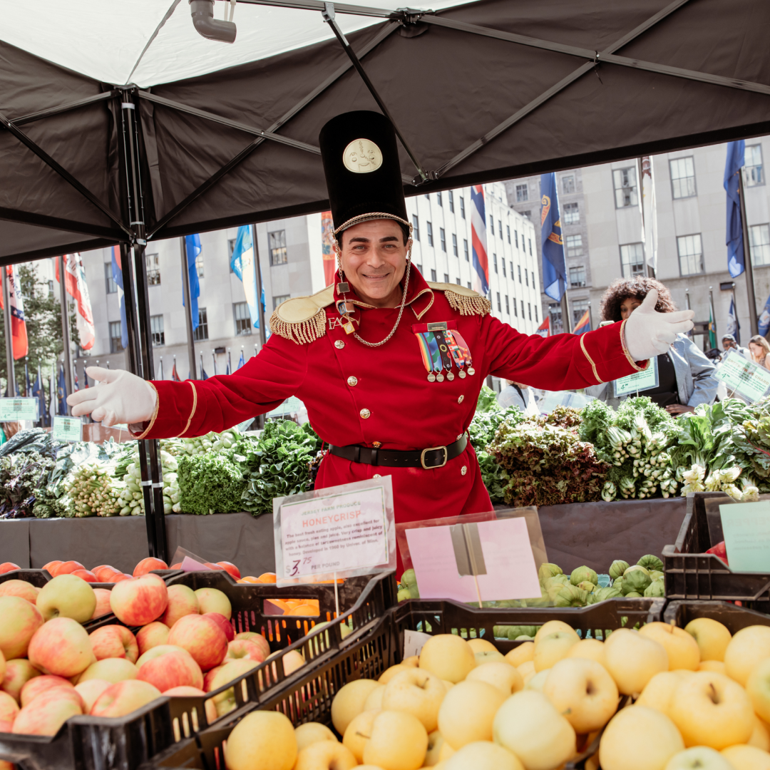 An FAO Schwarz toy soldier standing next to a fruit stand at the GrowNYC Greenmarket at Rockefeller Center