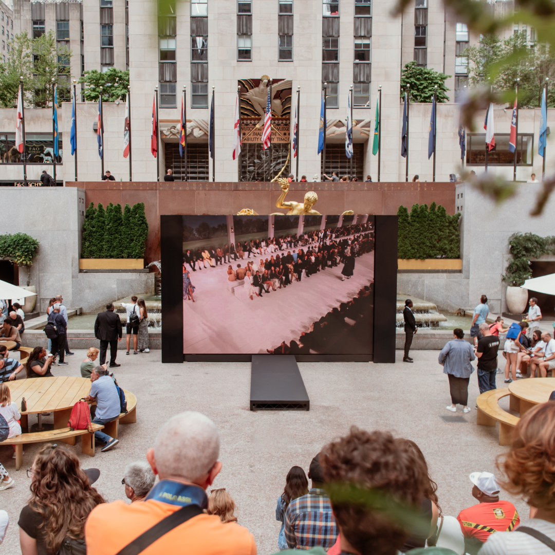 Groups of people watching live New York Fashion Week runway shows at Rockefeller Center