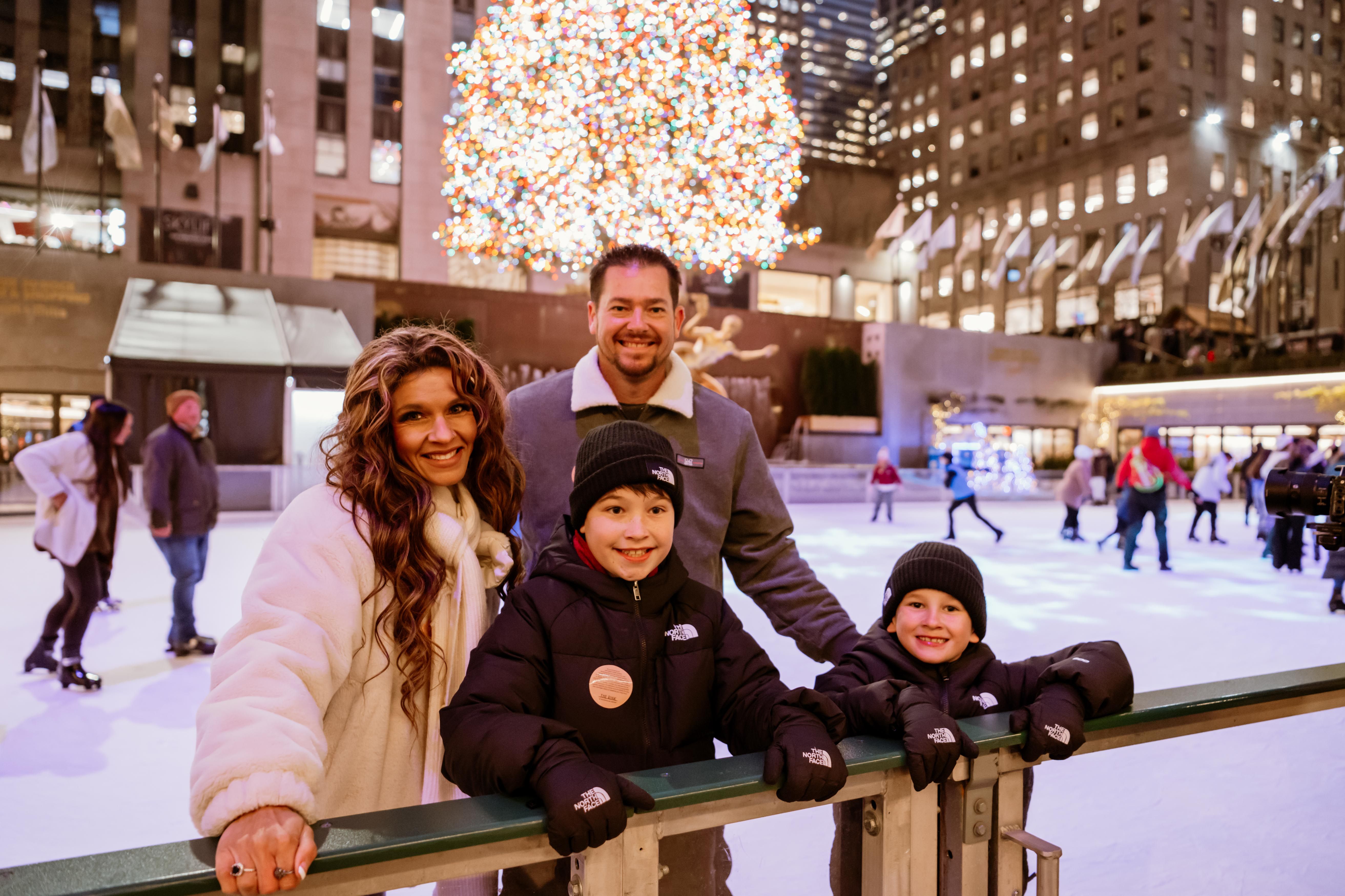 a family smiling on the rink at rockefeller center