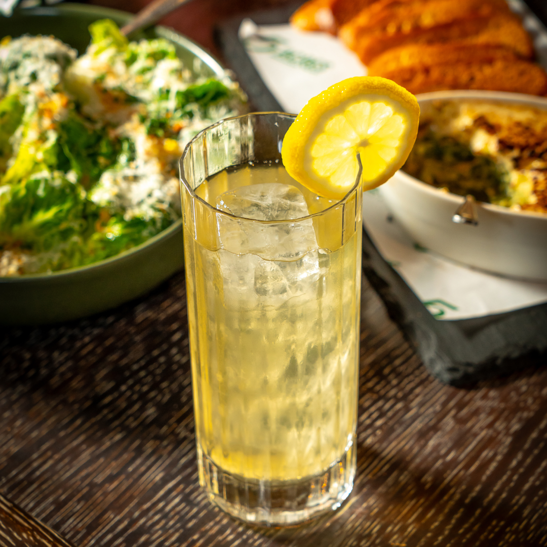 A tropical cocktail and plates of food from 5 Acres at Rockefeller Center