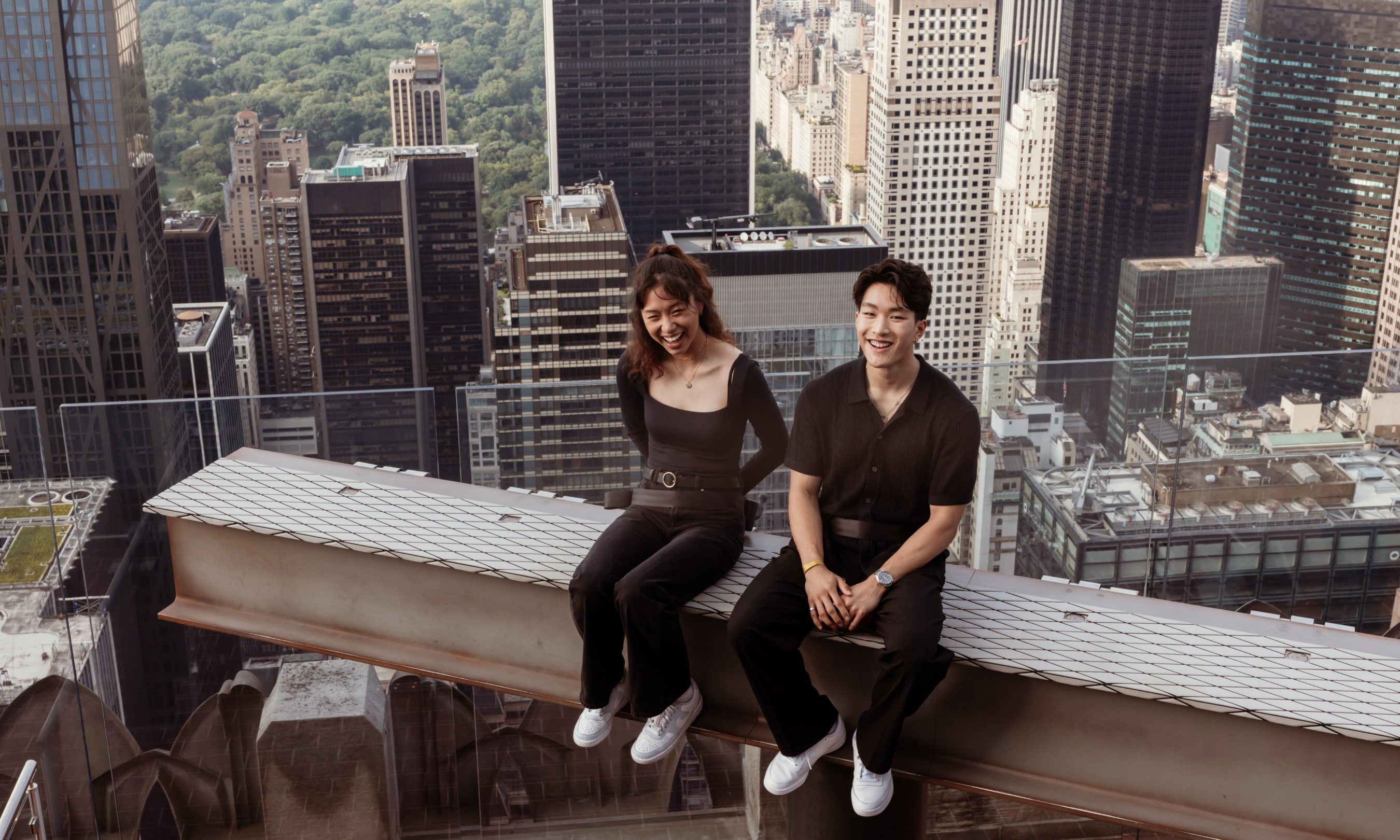 A couple sitting on The Beam at Top of the Rock