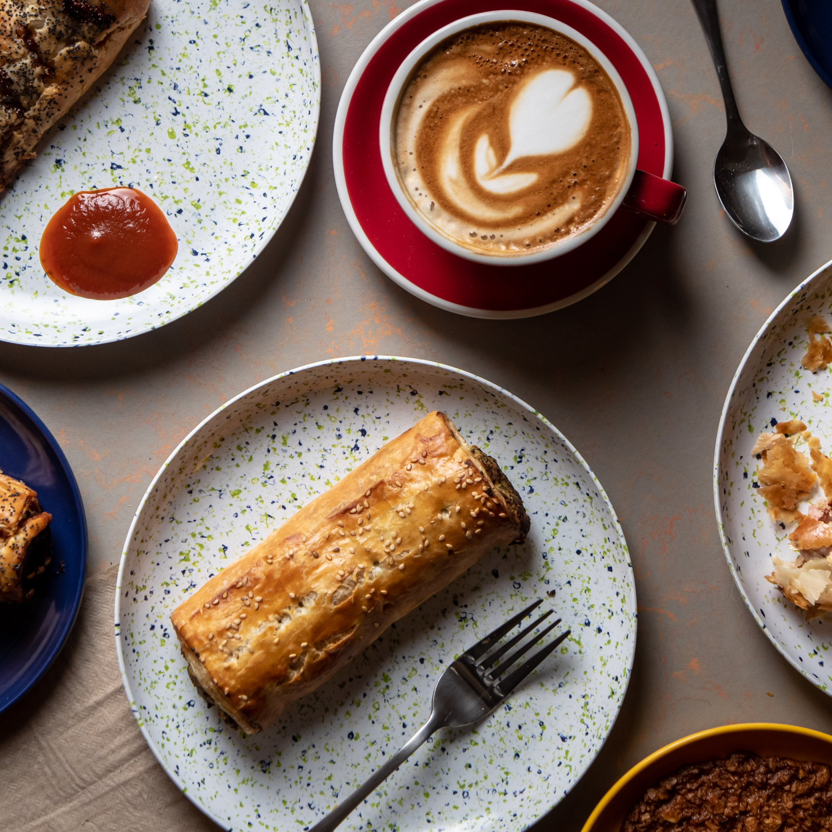 A cup of coffee and plates of breakfast items from Bourke Street Bakery at Rockefeller Center
