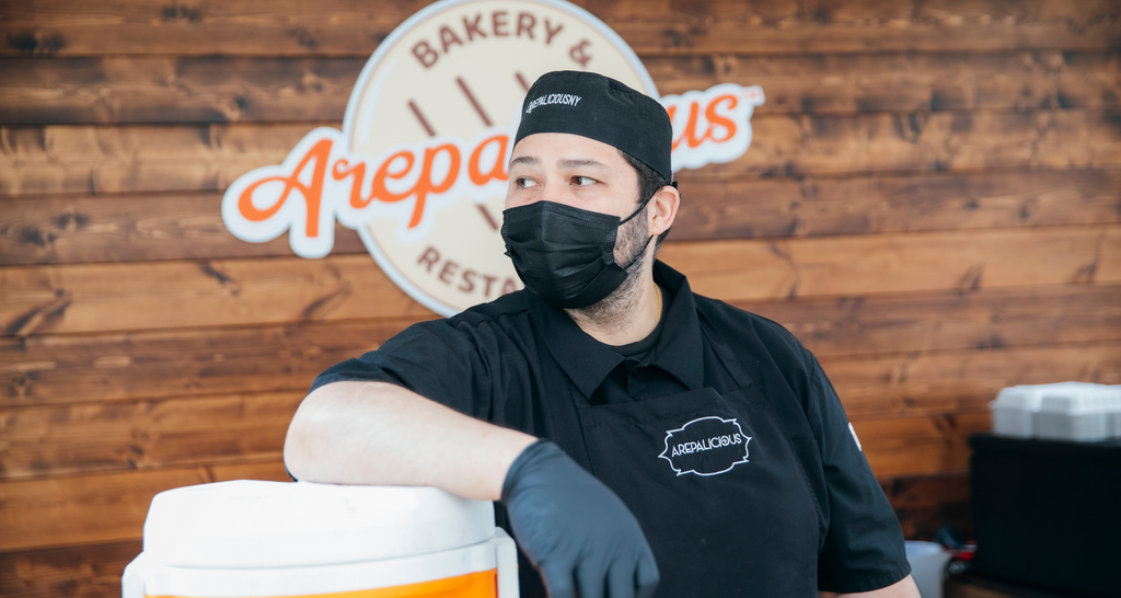 A employee standing in the Arepalicious stand at the Queens Night Market Outpost at Rockefeller Center 