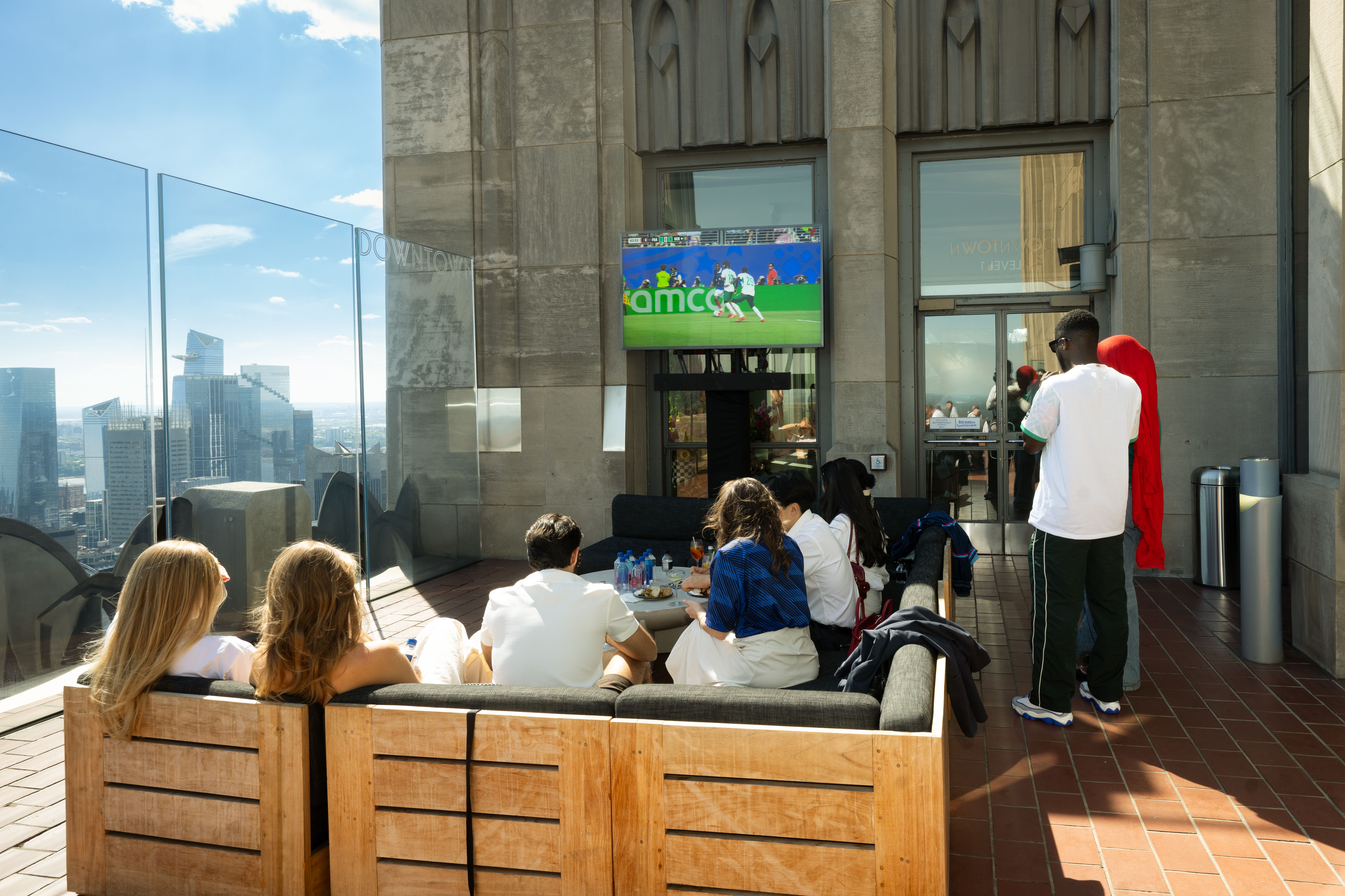 people watching the world cup on a tv screen at top of the rock
