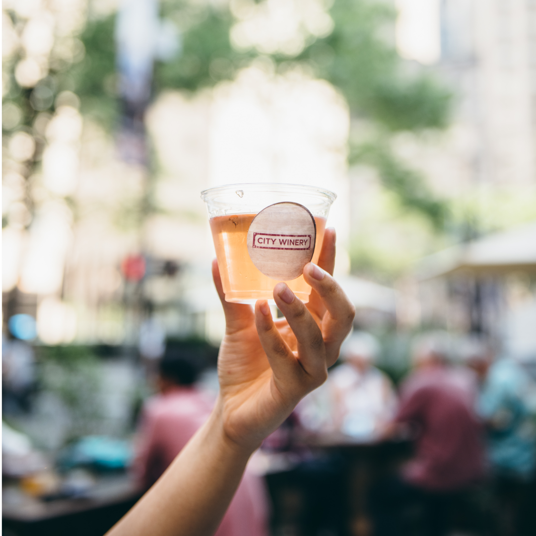 A hand holding a cup of wine from City Winery at Rockefeller Center