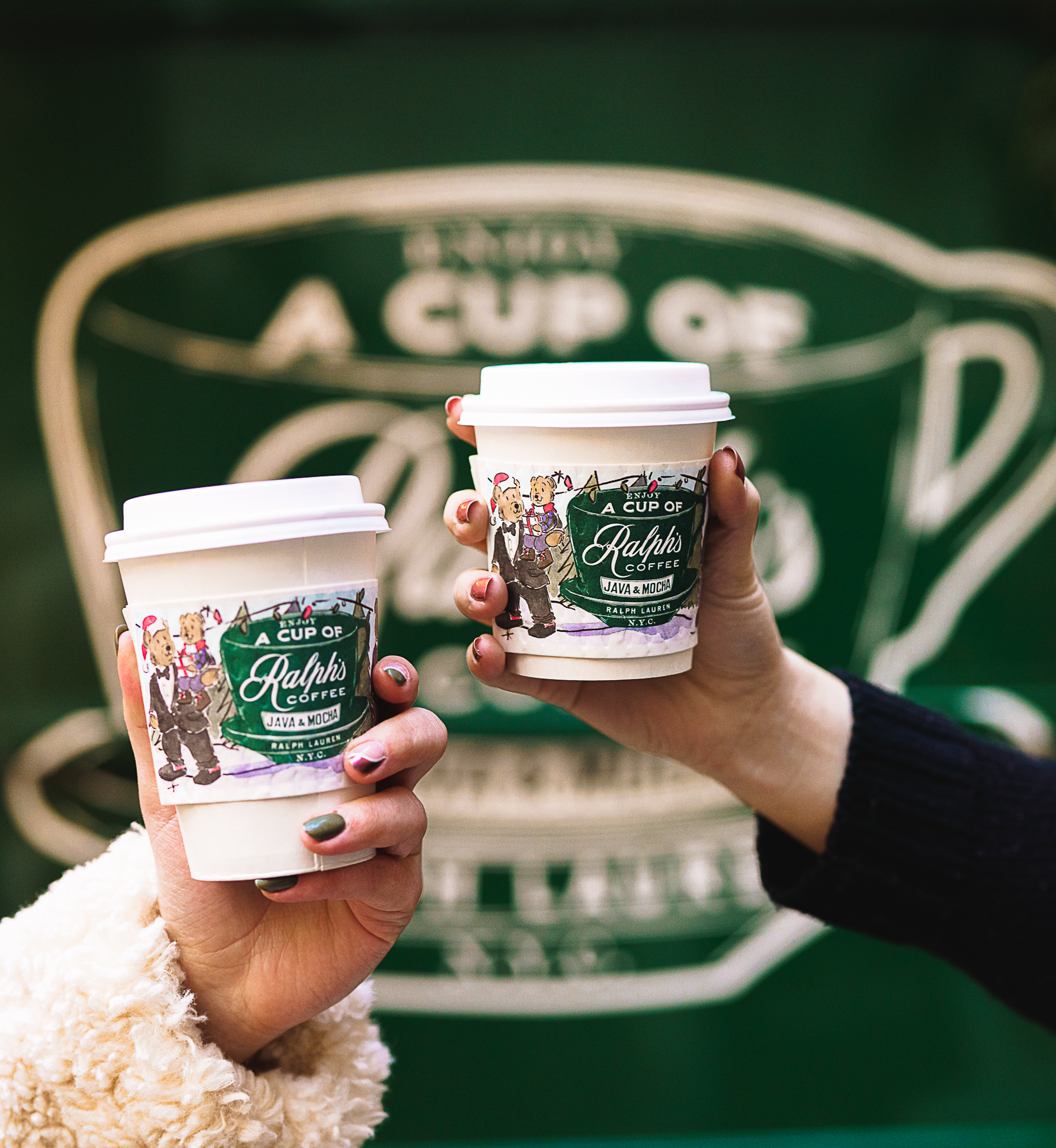 Two hands holding two cups of coffee from Ralph's Coffee Truck at Rockefeller Center