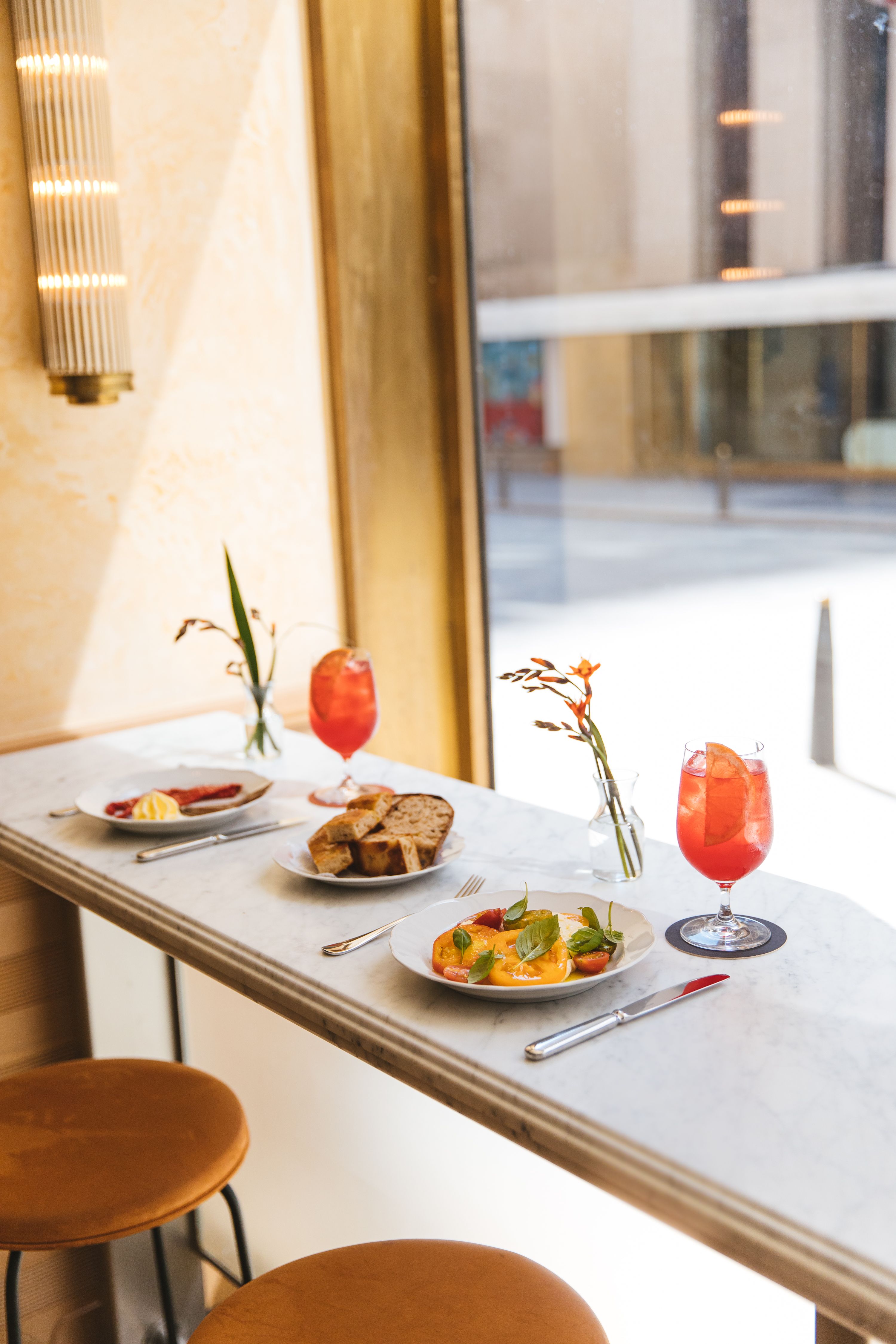 two place-settings with food and Aperol Spritz's at Lodi bar top 