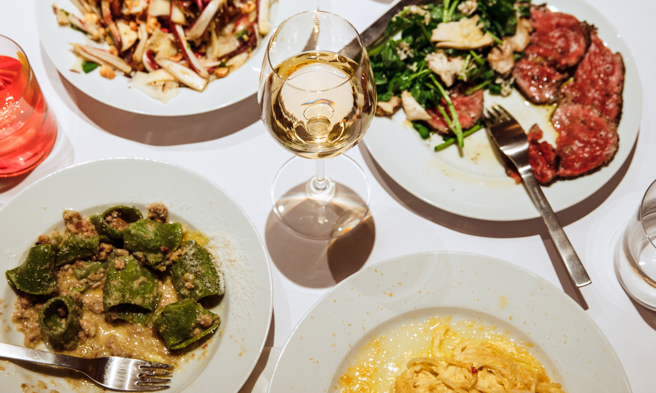 Glass of wine and plates of food from Jupiter at Rockefeller Center